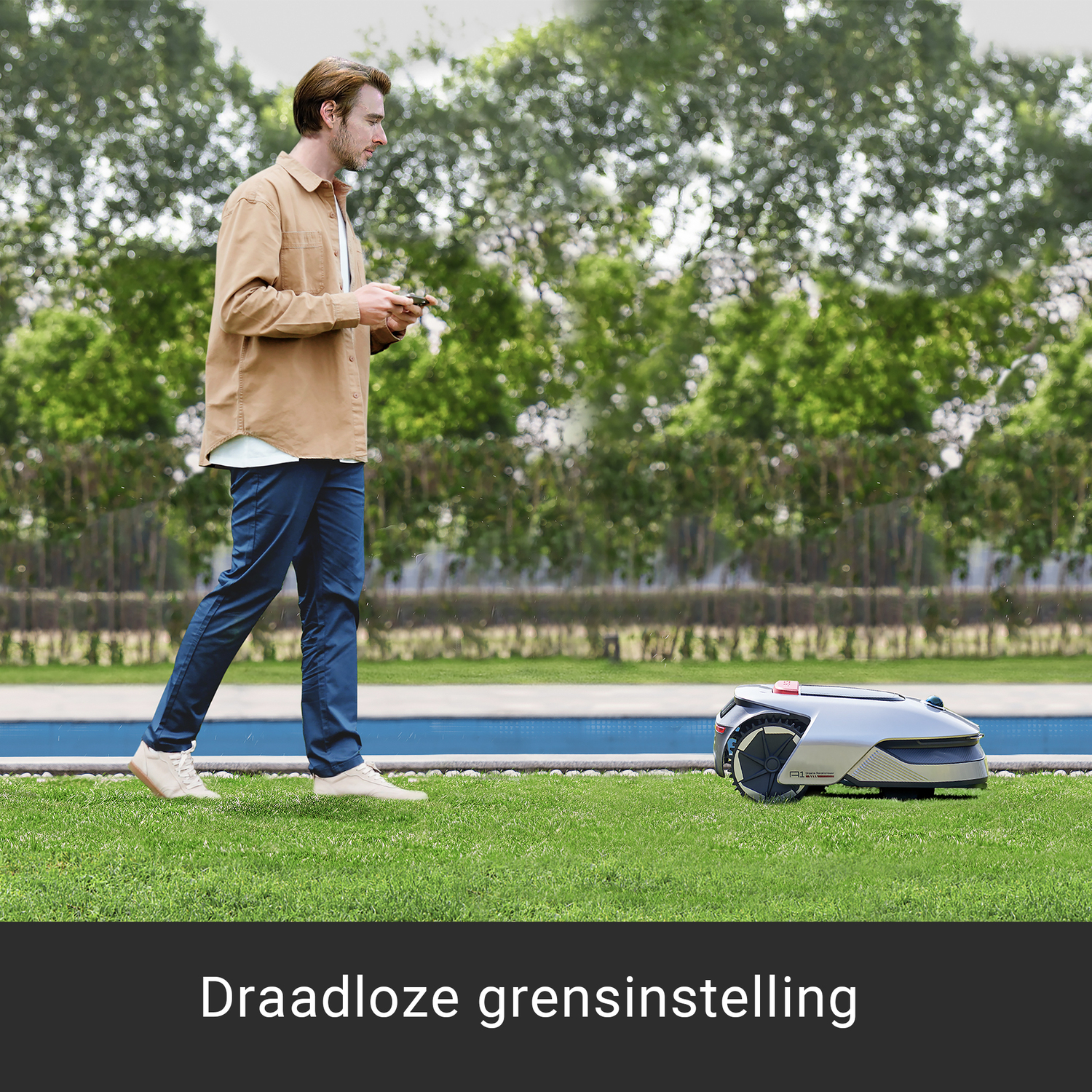 Man bestuurt een robotmaaier op groen gras, met bomen en een zwembad.
