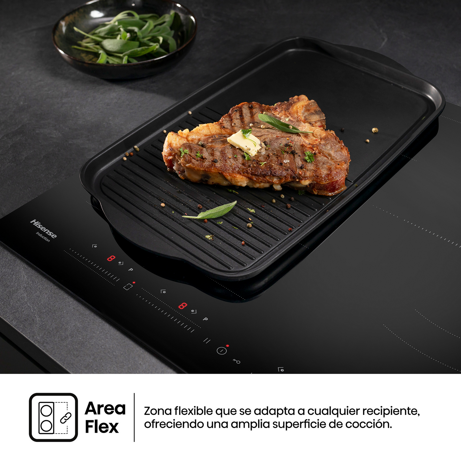 Una encimera de inducción negra con un bistec en una plancha y hierbas.