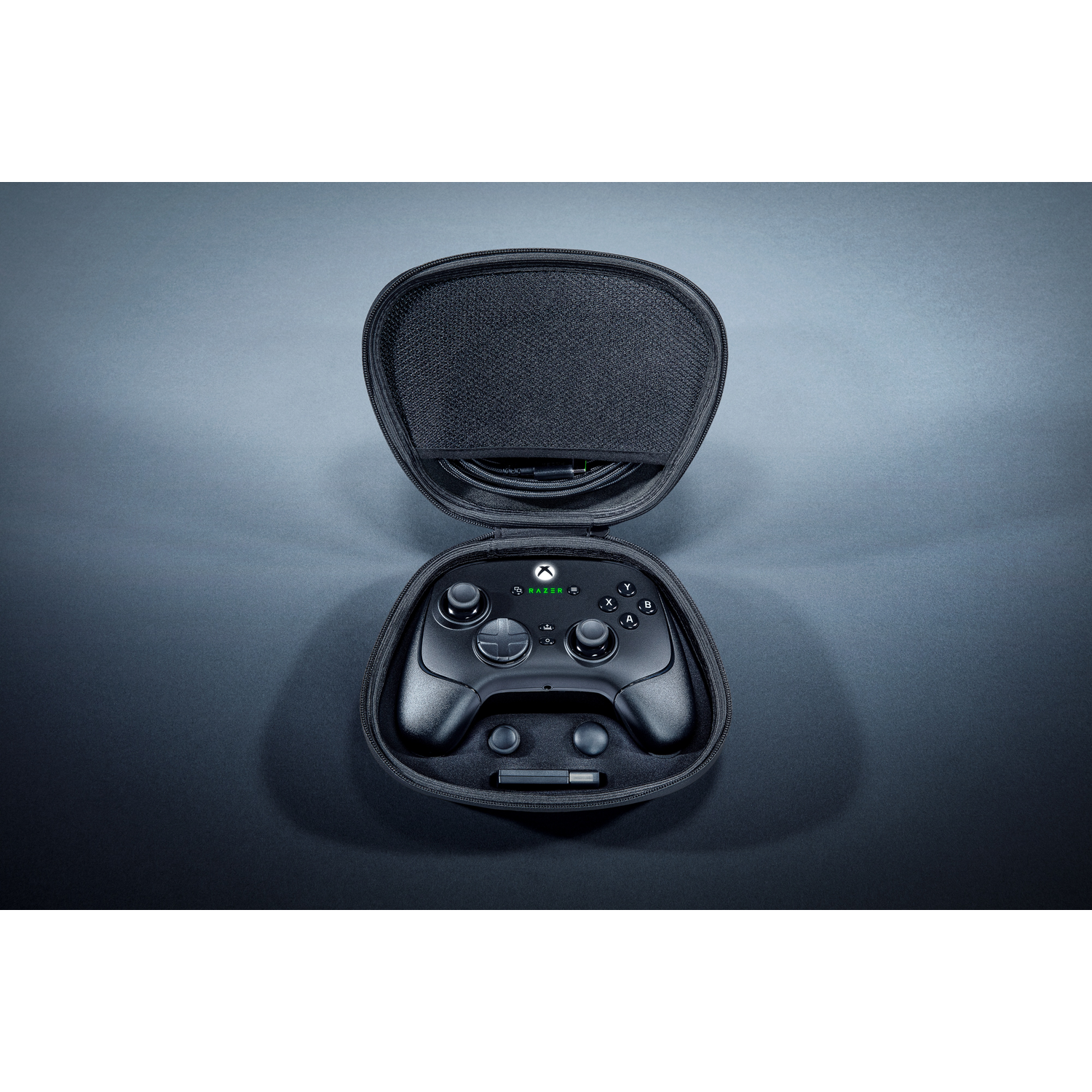 Black Xbox controller in an open black case. The case is on a dark grey surface.