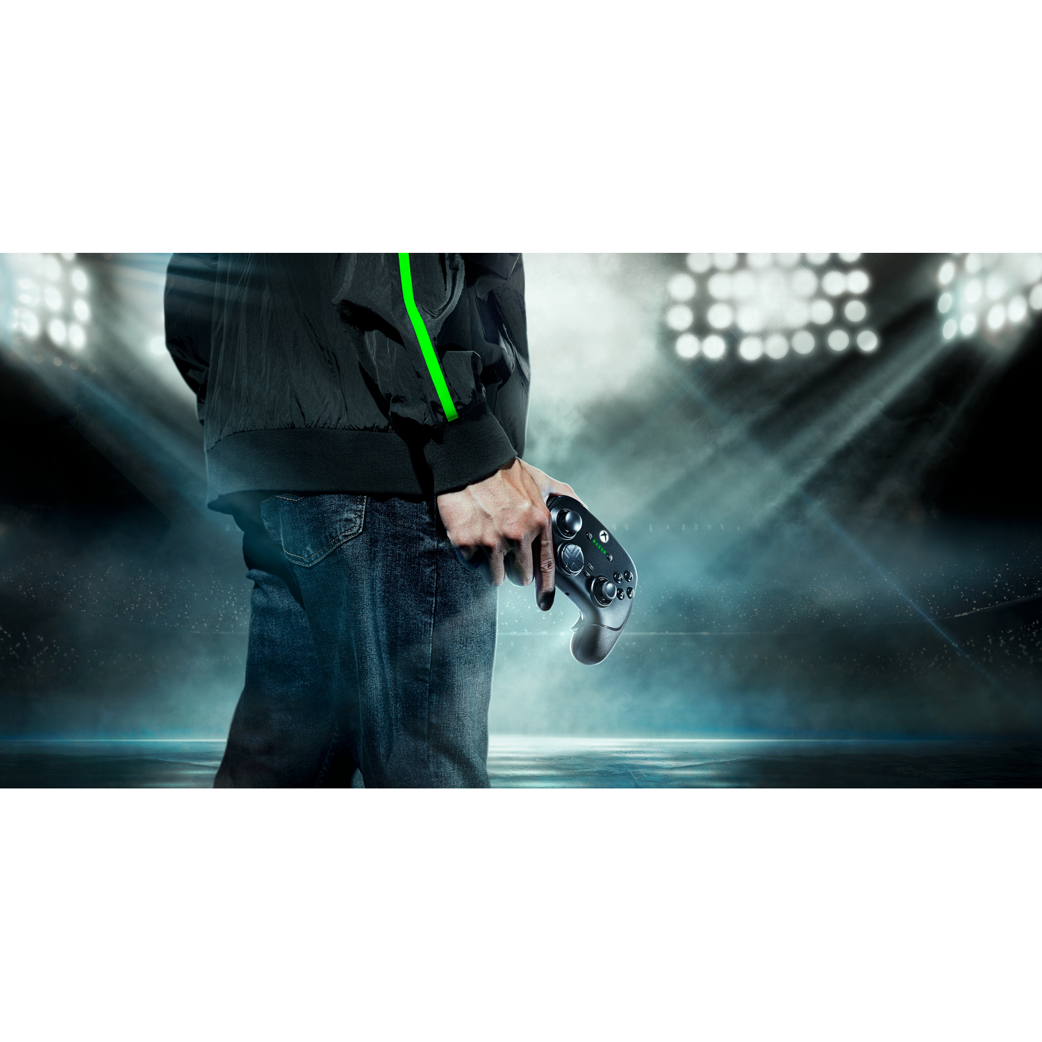 Person holding a black and grey game controller, with spotlights in the background.