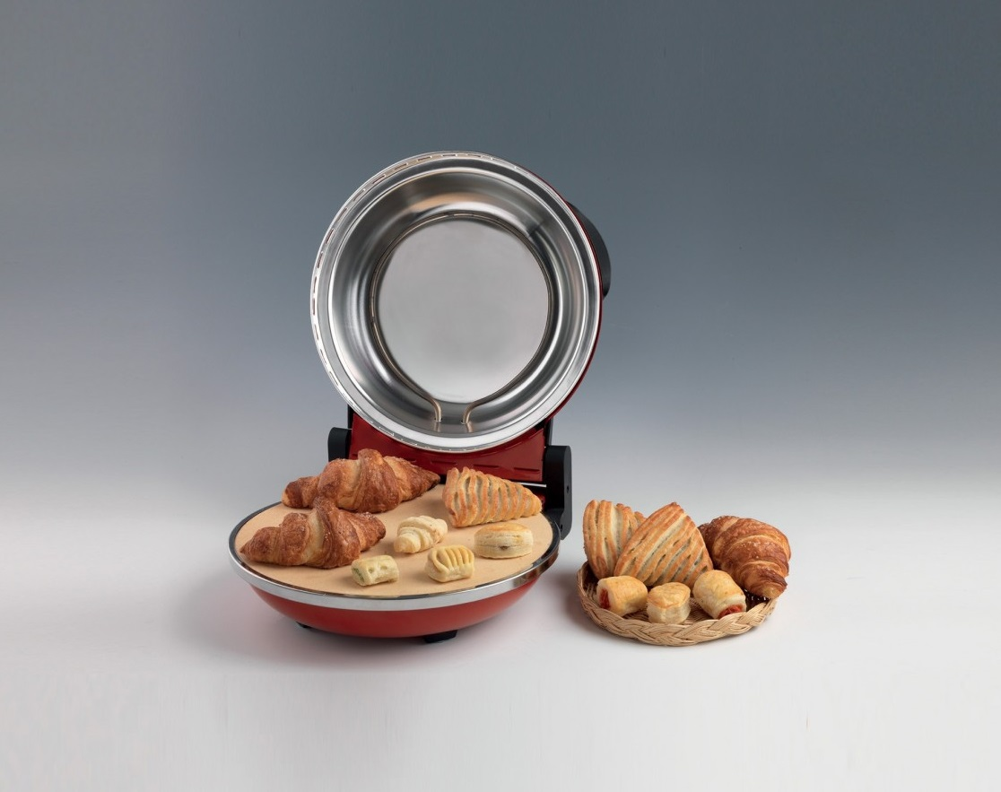 Czerwony mini piekarnik z otwartą pokrywą, rogaliki i ciastka na tacy i w koszu.