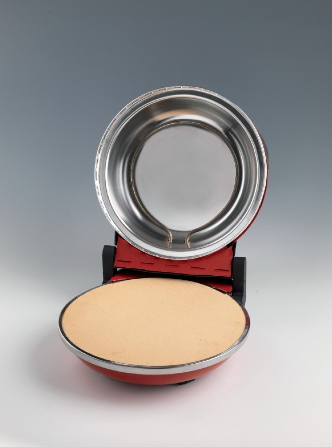 Czerwona i srebrna maszyna do pizzy, otwarta. Beżowa baza pizzy na dole.