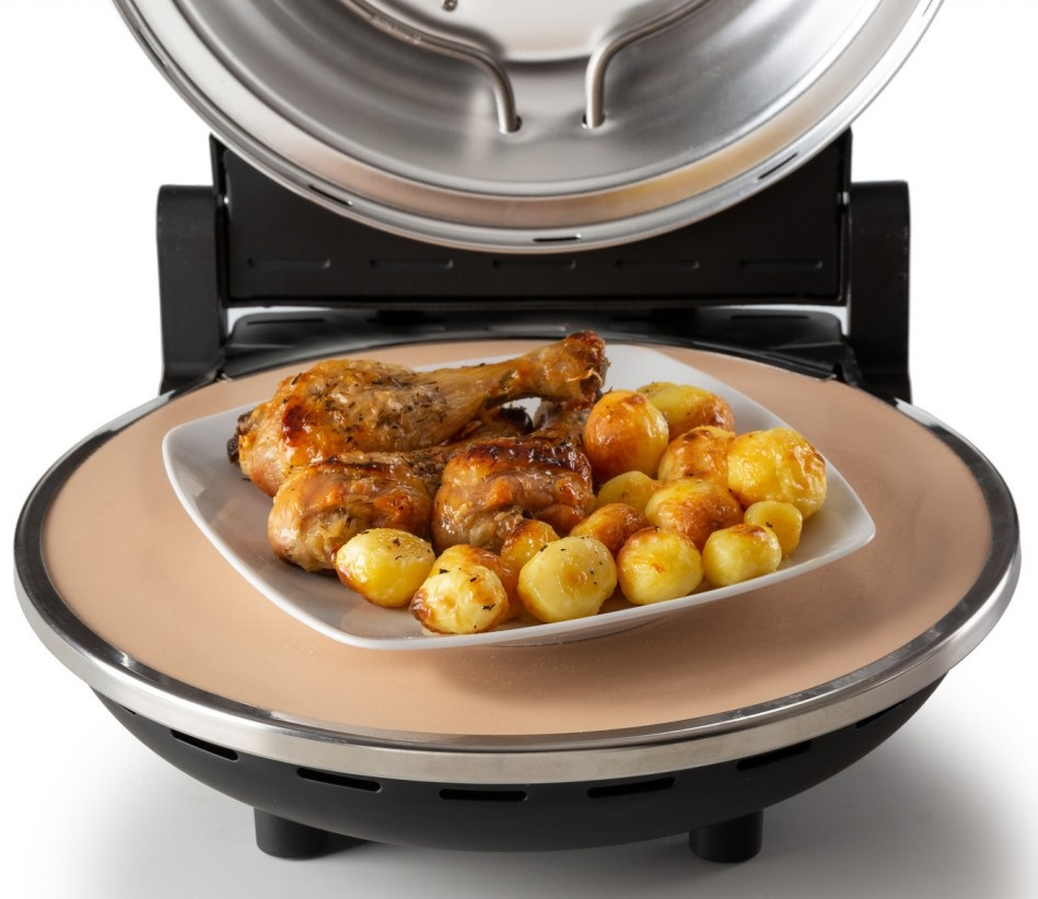 Pieczony kurczak i ziemniaki na białym talerzu wewnątrz piekarnika na blacie z otwartą pokrywą.