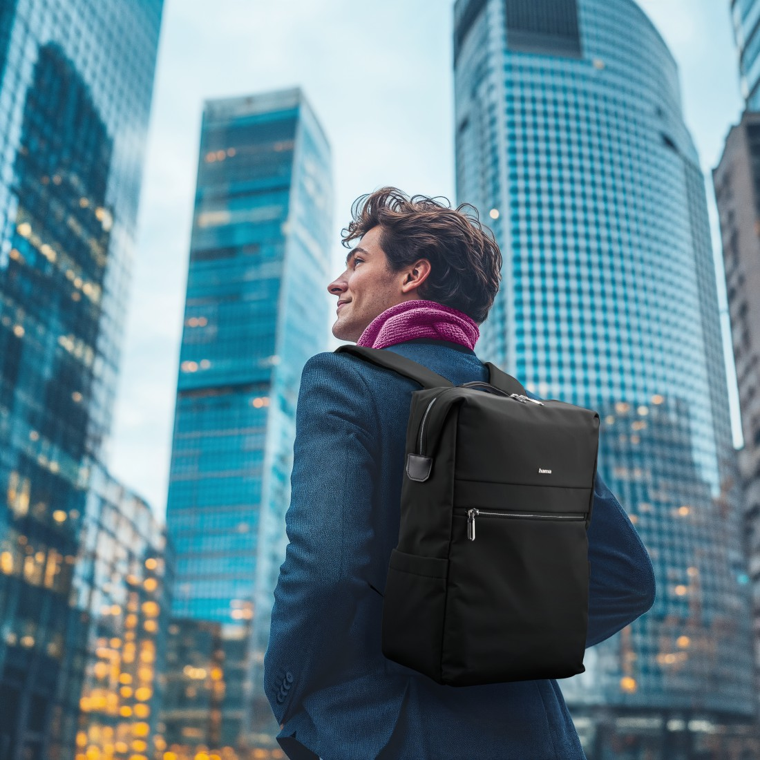 Ein Mann mit einem schwarzen Rucksack steht in einer Stadt mit Wolkenkratzern.