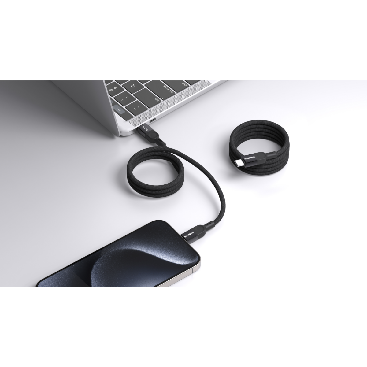 Beyaz bir yüzeyde bir dizüstü bilgisayara ve akıllı telefona bağlı bir USB-C konektörlü siyah kablo.
