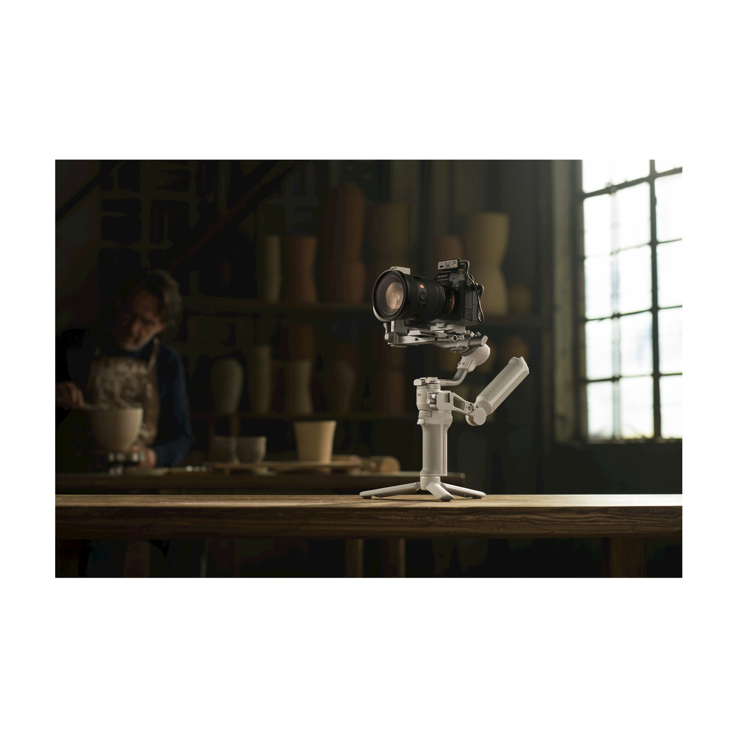 Fotocamera montata su un gimbal bianco, con una persona sullo sfondo.