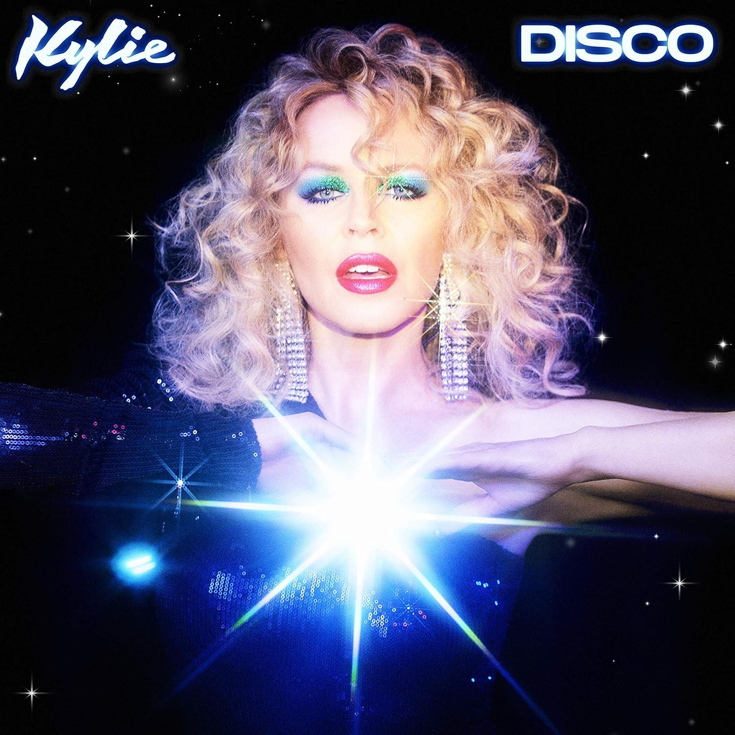 Kylie 'Disco' album borítója. Kylie egy fényes fénnyel áll előtte. Csillagok és csillogás a háttérben.