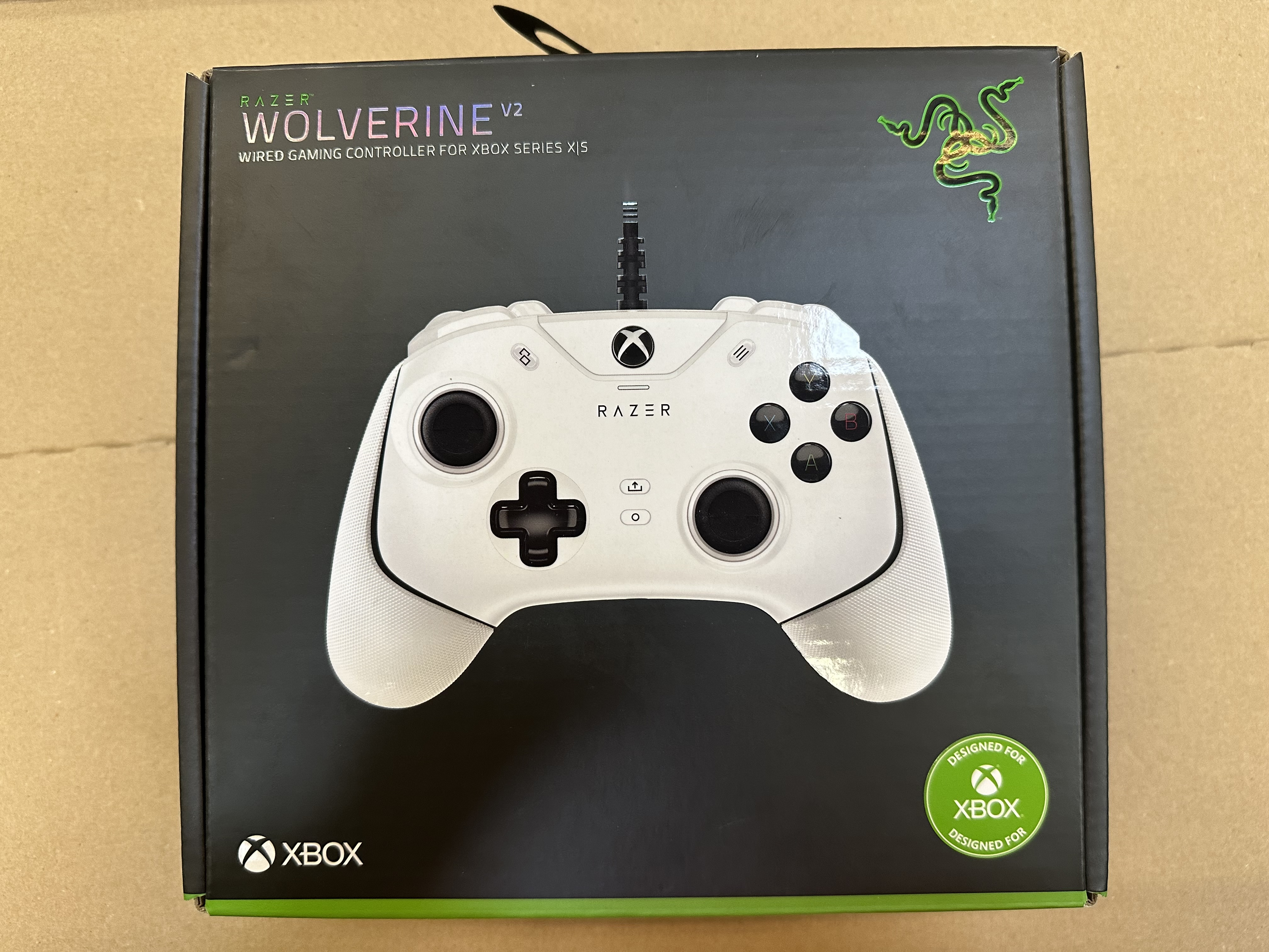 Biały kontroler Razer Wolverine V2 w czarnym pudełku. Logo i design Xbox na pudełku.