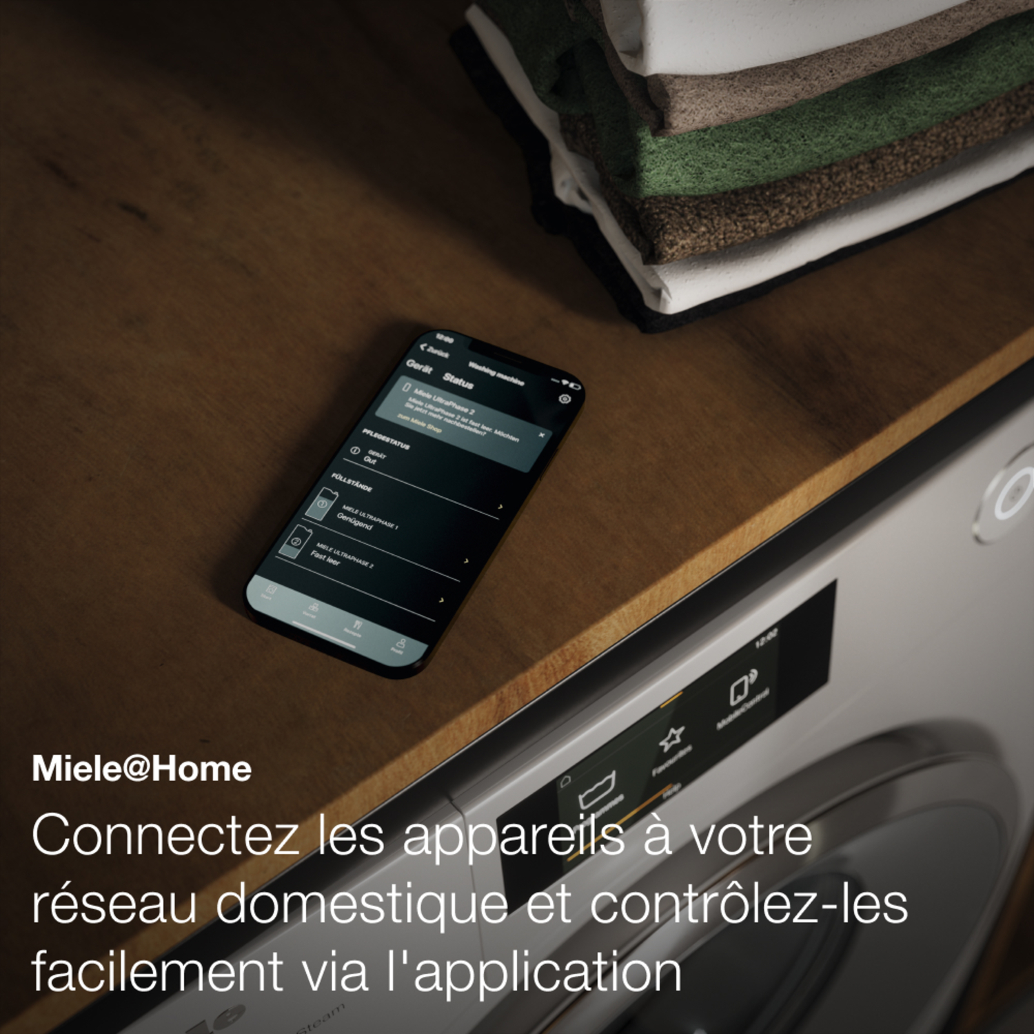 Un téléphone affiche l'état de la machine à laver. Le téléphone est sur une surface en bois.