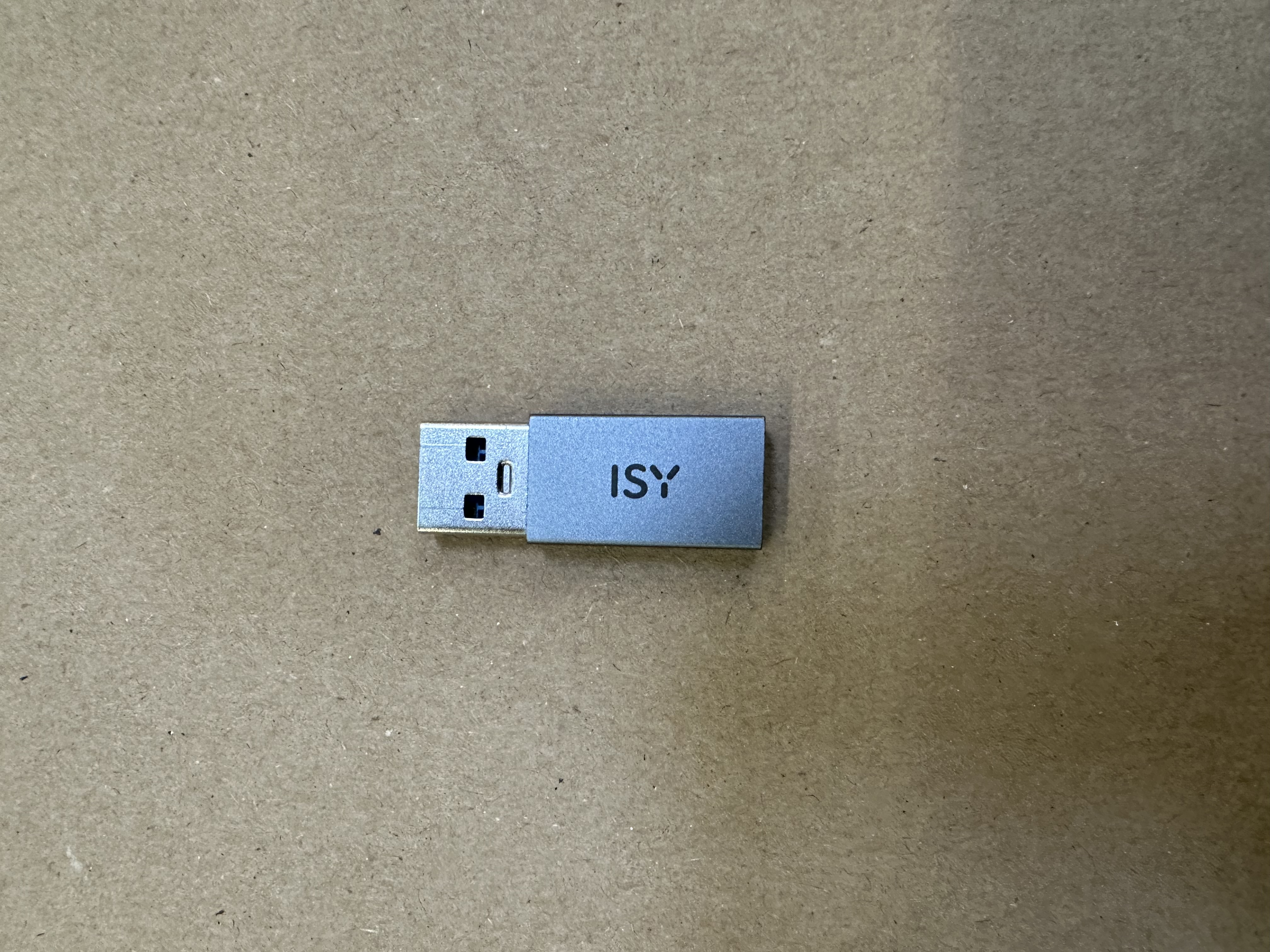 Srebrny pendrive z napisem 'ISY' na brązowej powierzchni.
