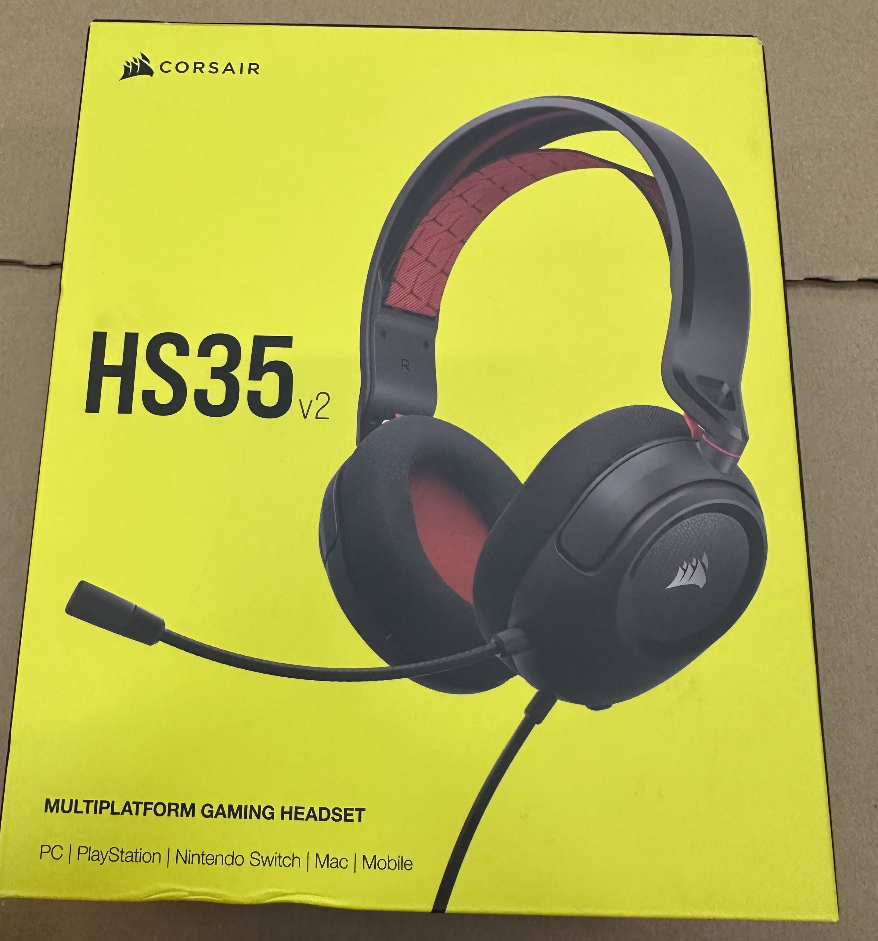 Żółte pudełko z czarno-czerwonym zestawem słuchawkowym dla graczy. Na pudełku napis HS35 V2, Corsair i Multiplatform Gaming Headset.