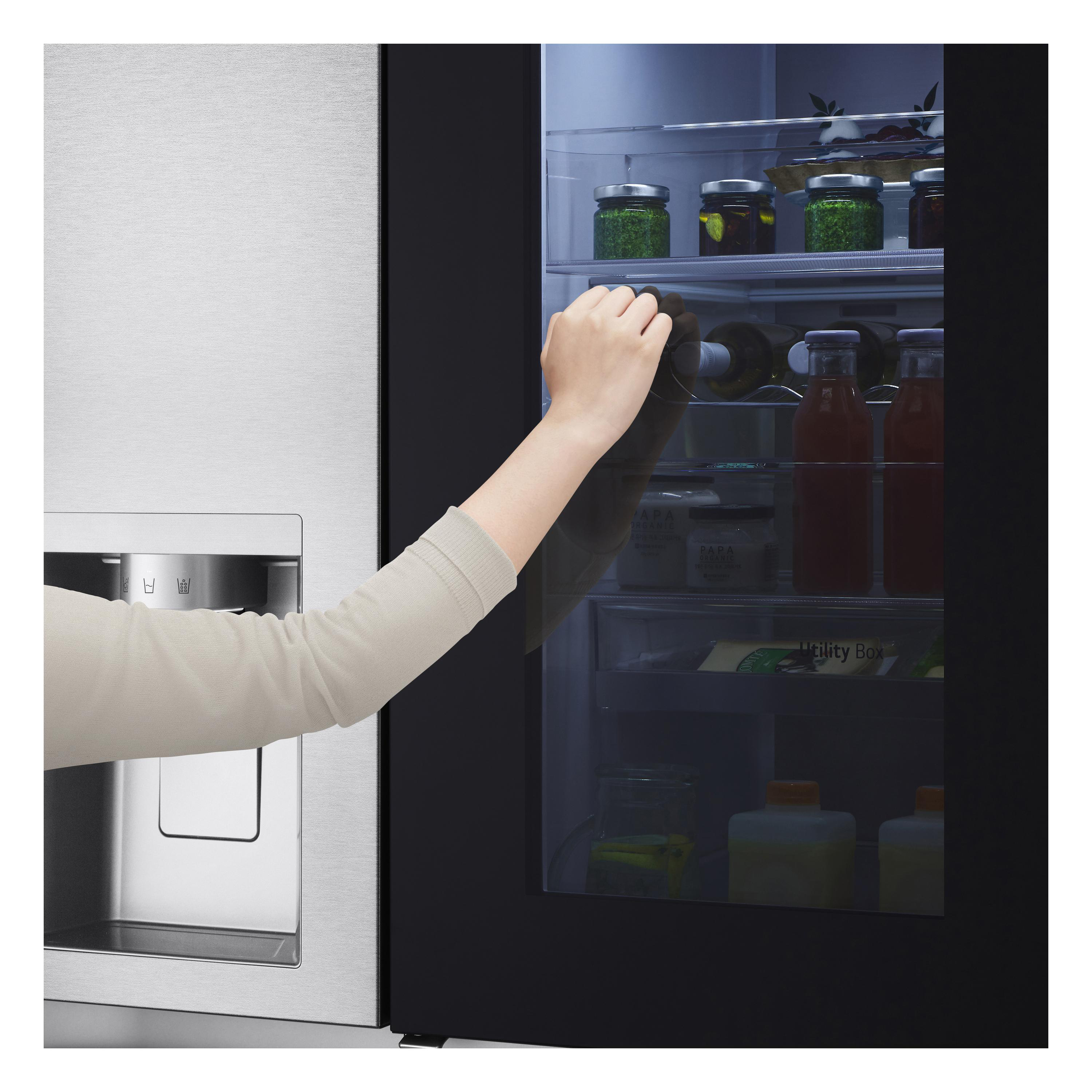 Die Hand einer Frau greift nach einer Weinflasche in einem Kühlschrank.