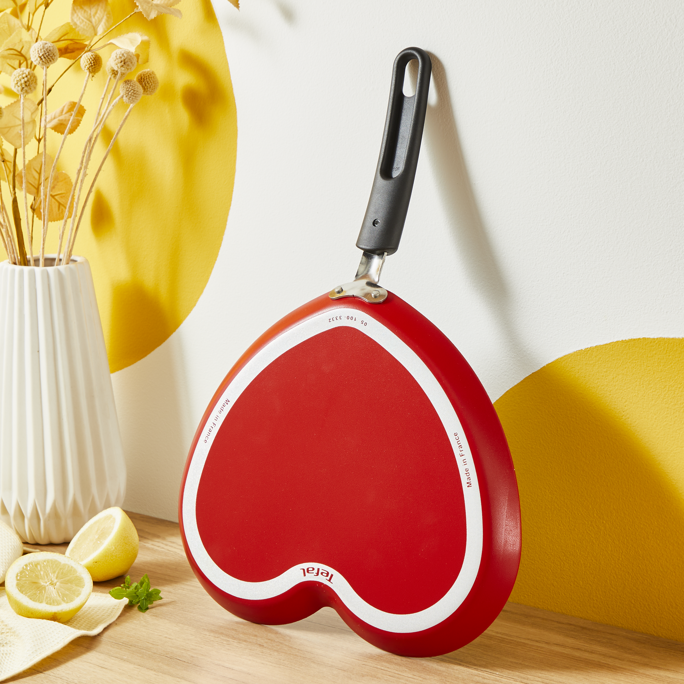 Czerwona patelnia w kształcie serca z białym obramowaniem na drewnianej powierzchni.