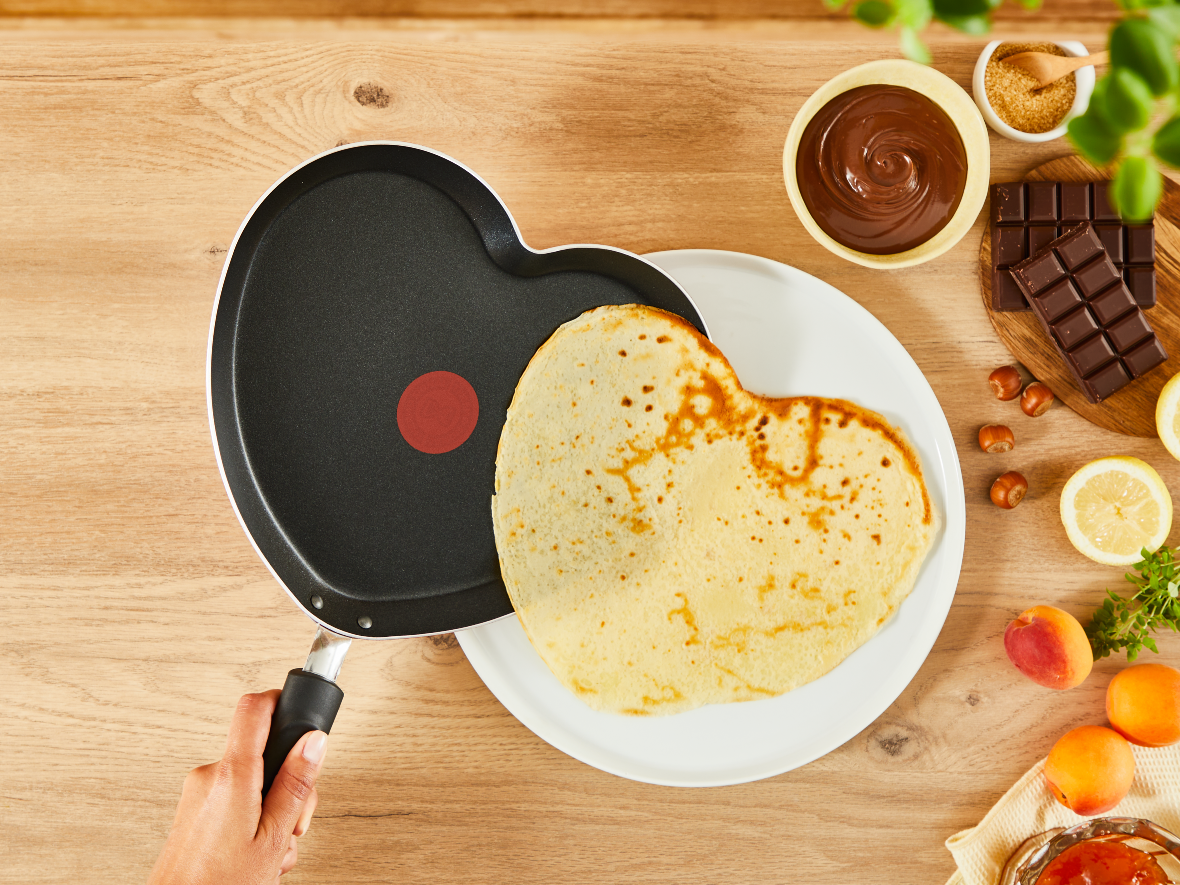 Naleśnik w kształcie serca na patelni w kształcie serca, otoczony składnikami.