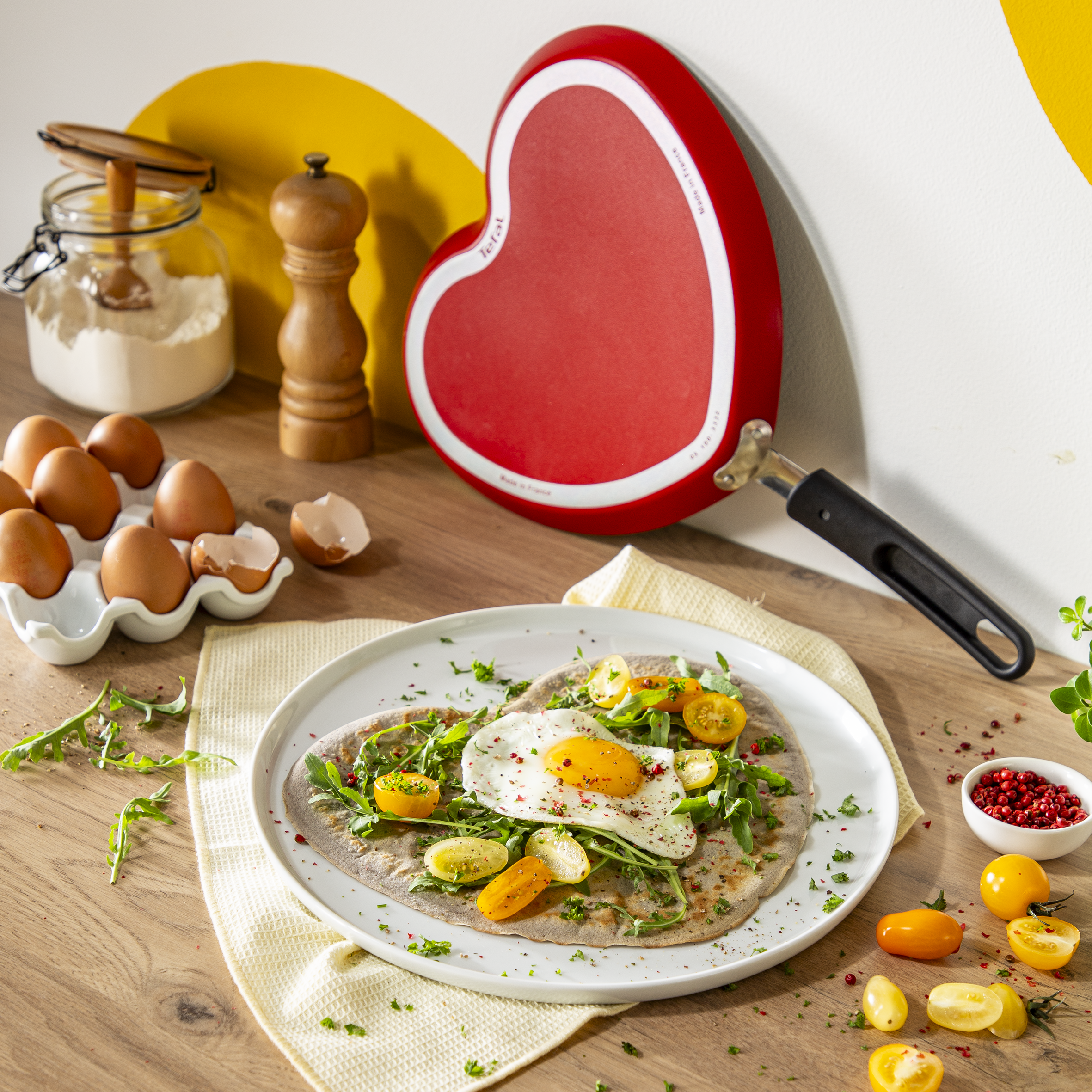 Czerwona patelnia w kształcie serca z jajkiem i jedzeniem na talerzu.