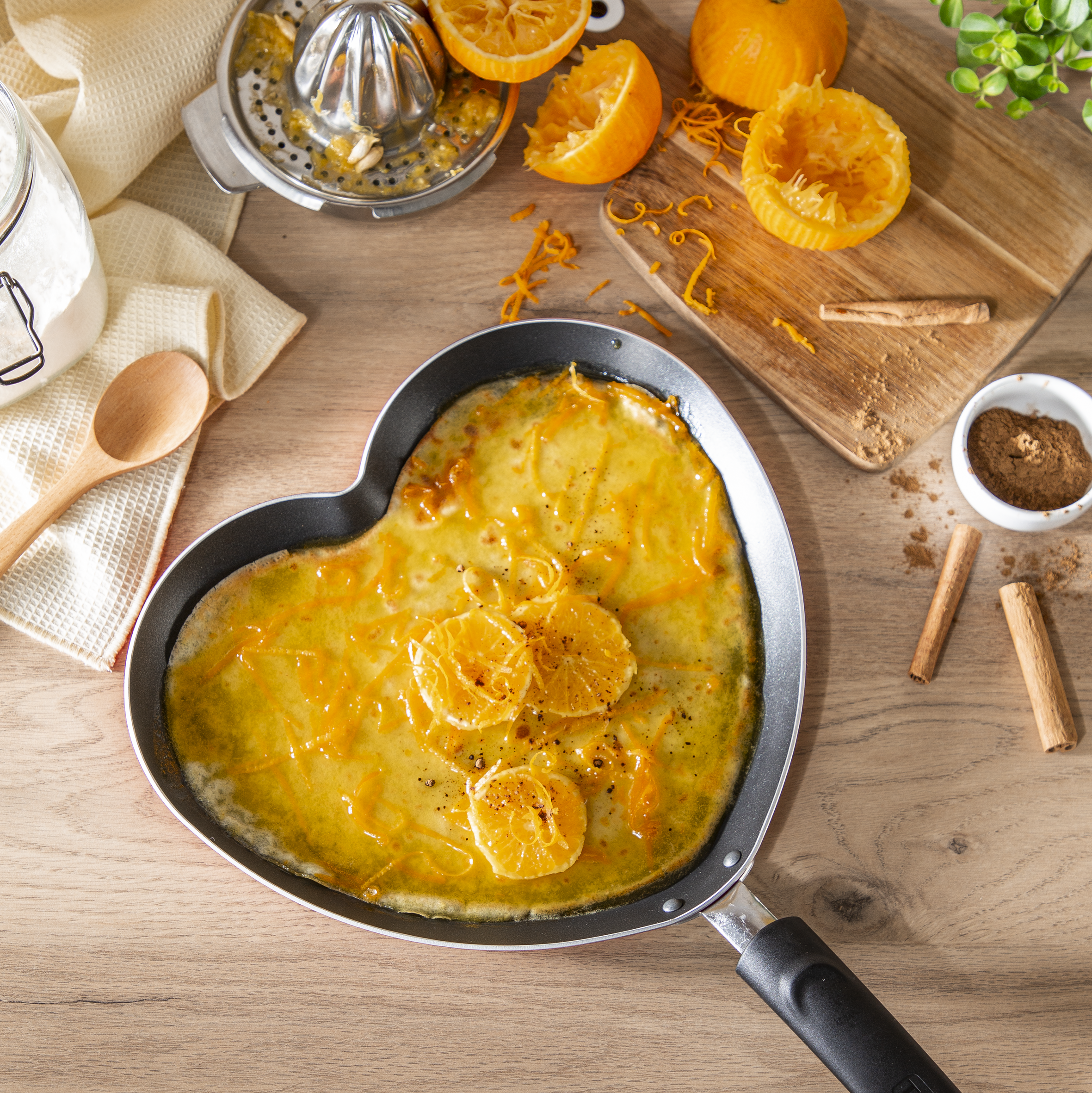 Patelnia w kształcie serca z naleśnikami pomarańczowymi, plasterkami pomarańczy i cynamonem.