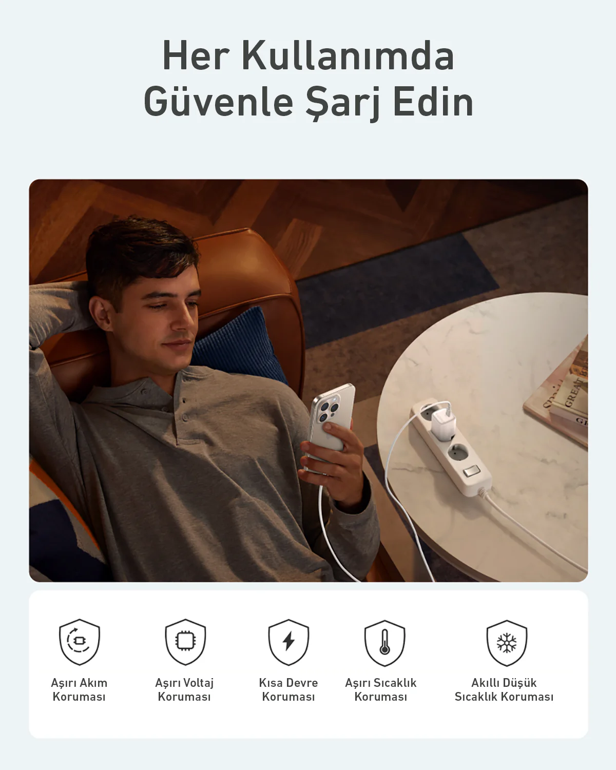 Adam telefon tutuyor. Beyaz bir priz duvarına takılı. Metin: Her seferinde güvenle şarj edin.
