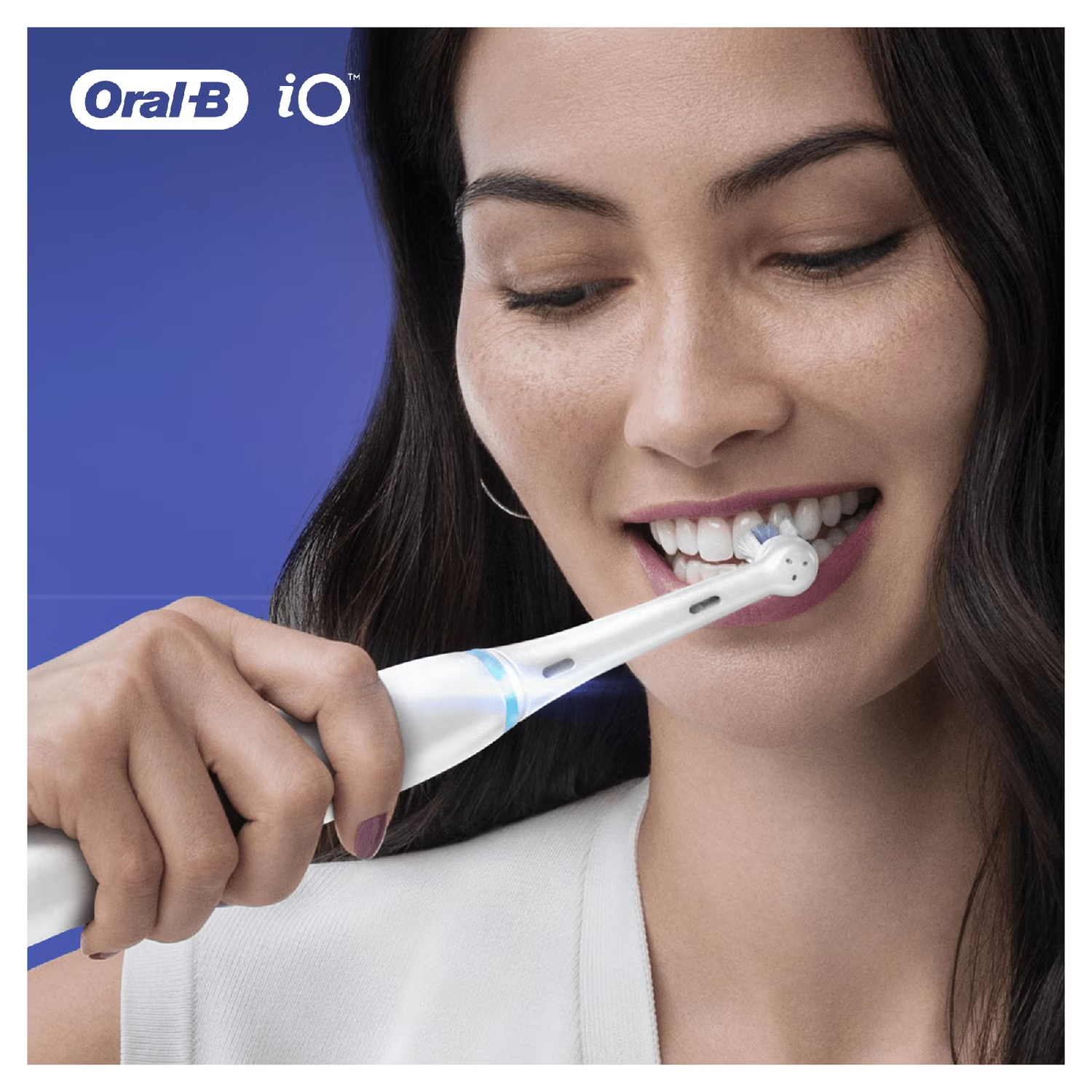 Una donna che si lava i denti con uno spazzolino elettrico bianco e blu, ripresa da vicino.