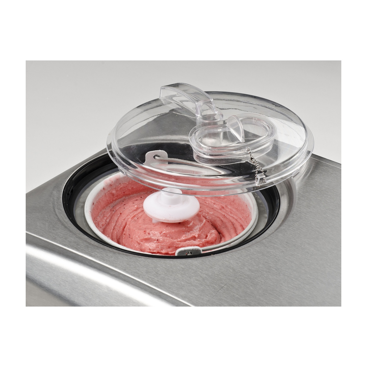 Una gelatiera con gelato rosa all'interno e un coperchio trasparente aperto.