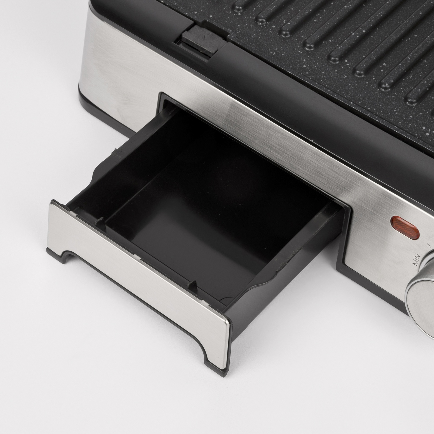 Primo piano di una griglia elettrica nera e argento con il cassetto aperto.