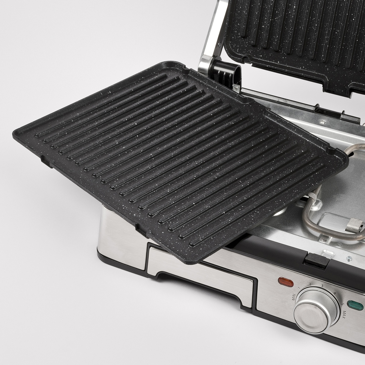 Piastra nera per grill su una griglia da appoggio argentata e nera, primo piano, sfondo bianco.