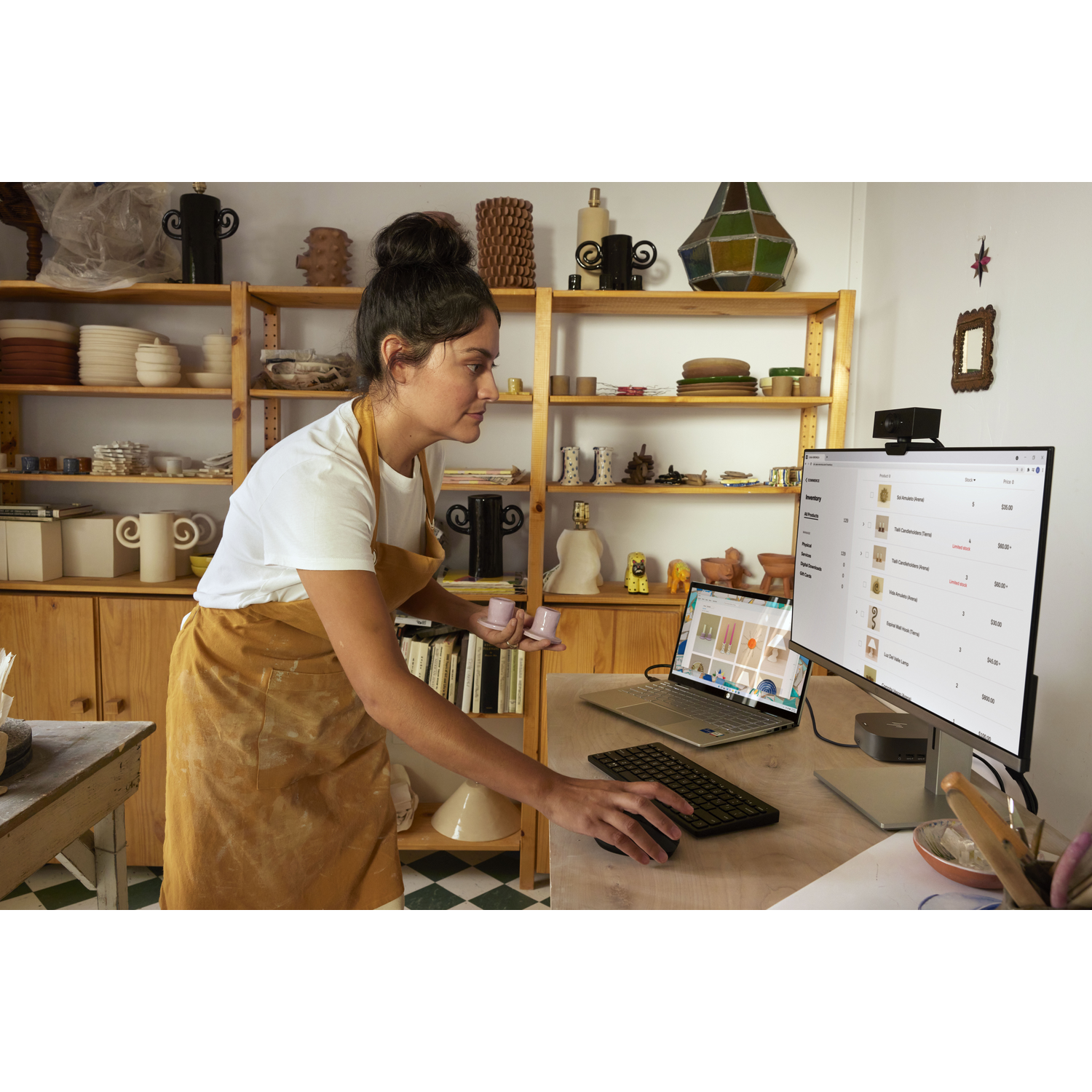 Vrouw in een pottenbakkerij, werkend aan een bureau met een laptop.