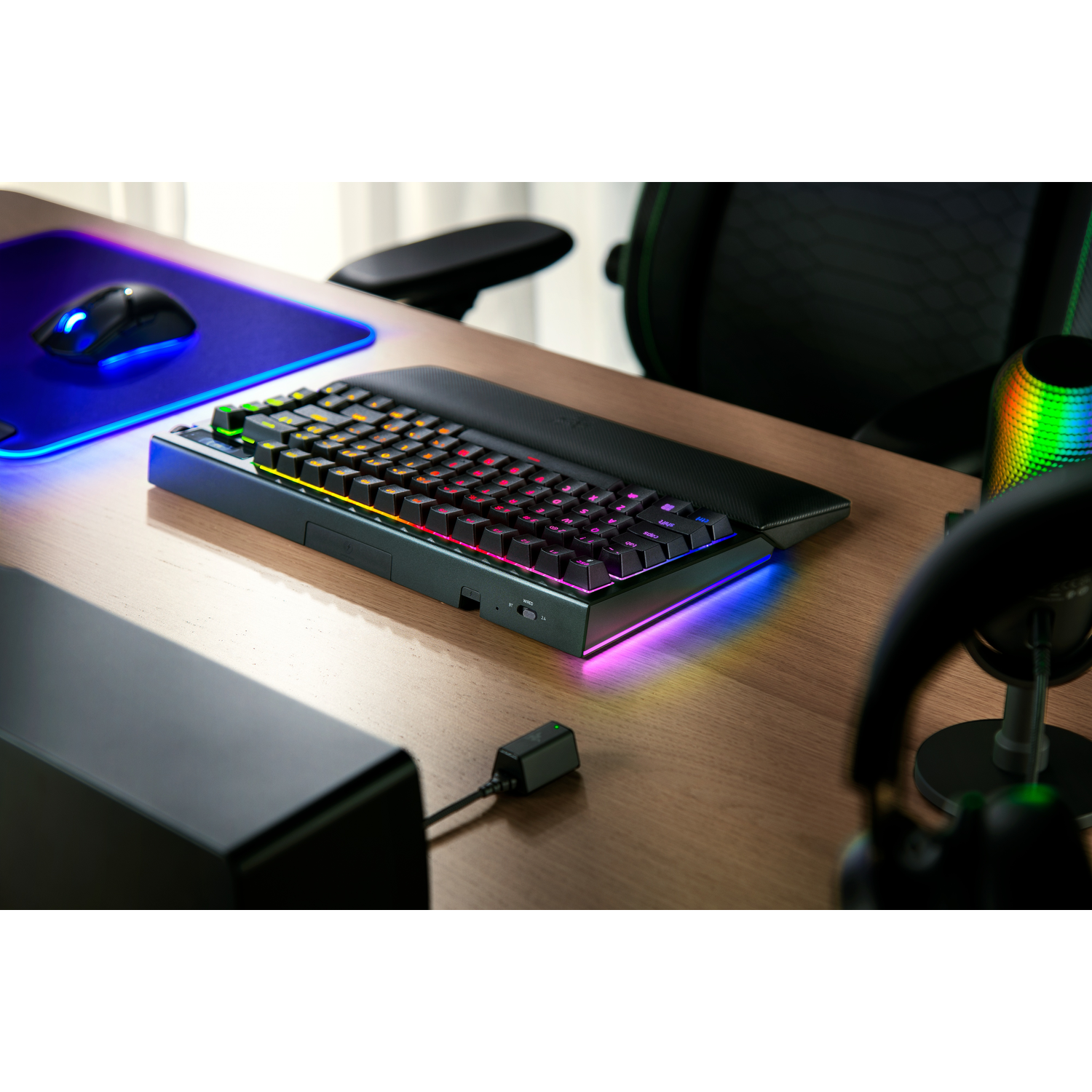 Gamingtoetsenbord op bureau met muis, koptelefoon en RGB-verlichting.