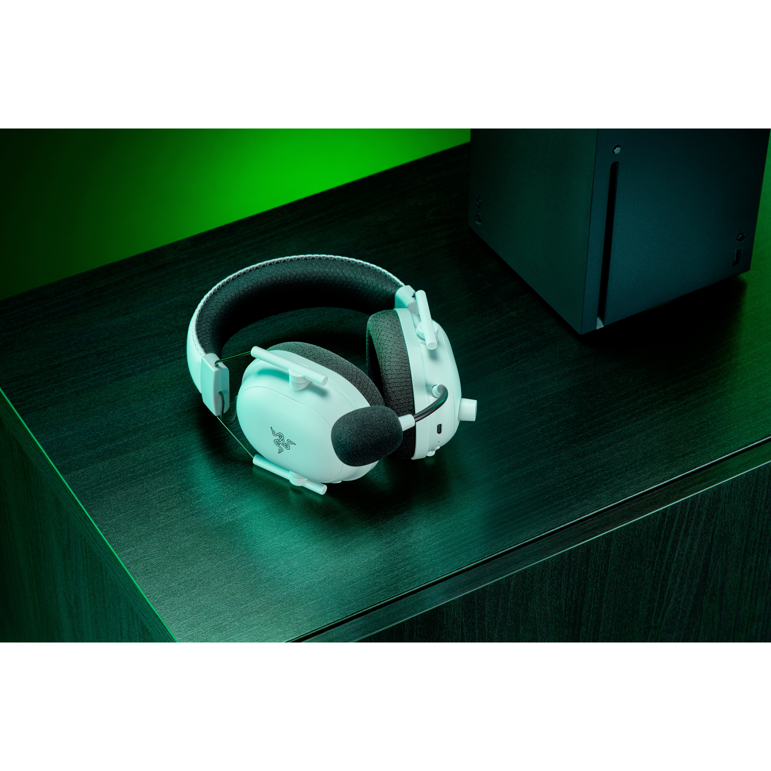 Casque de jeu blanc sur une surface vert foncé à côté d'un appareil noir.