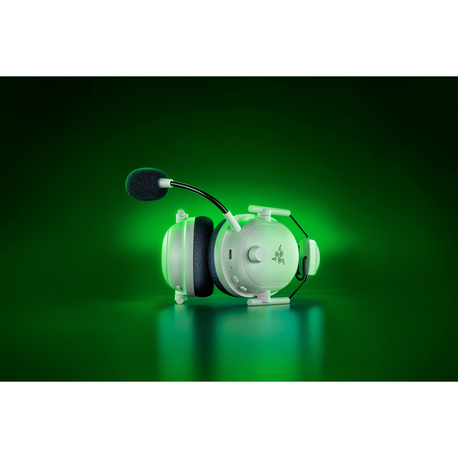 Casque de jeu blanc avec un microphone, posé sur un fond dégradé vert.