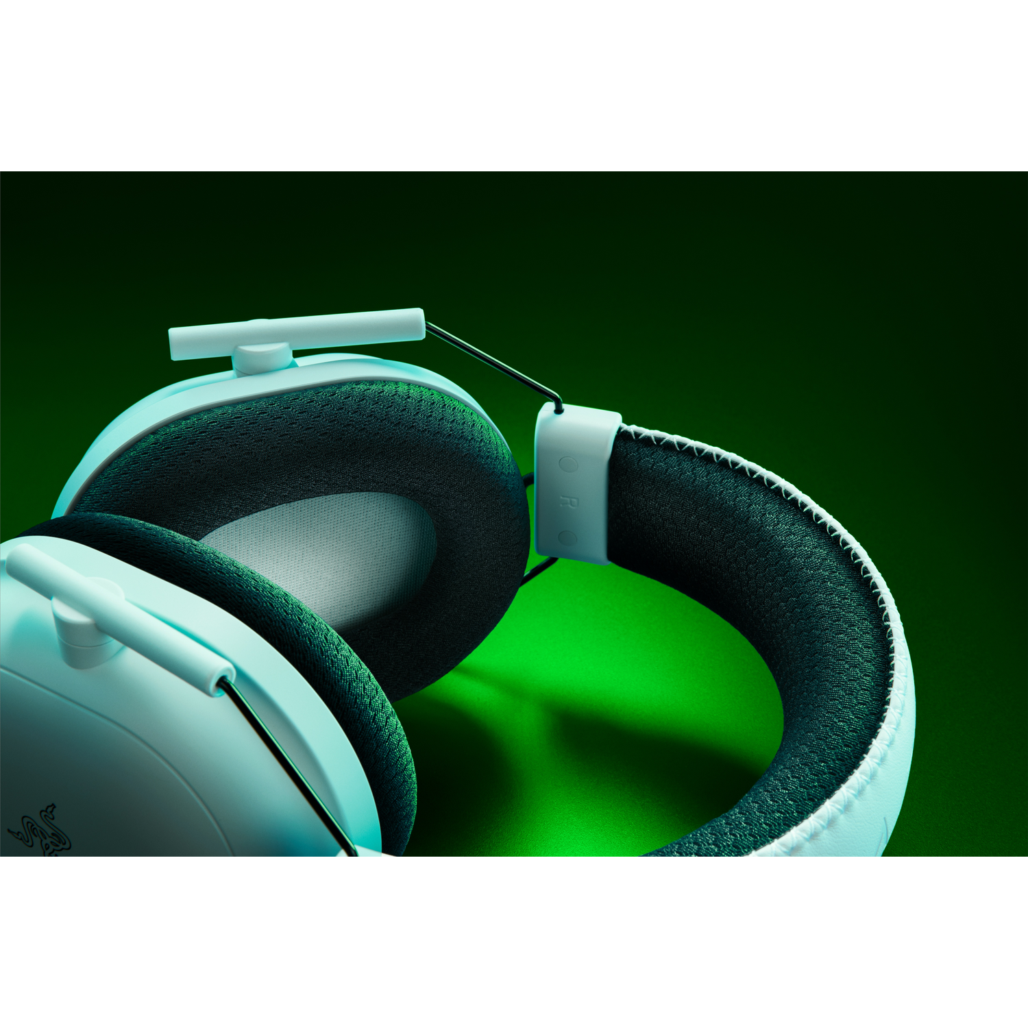Gros plan d'un casque de jeu bleu clair. Fond vert. Marque Razer visible.