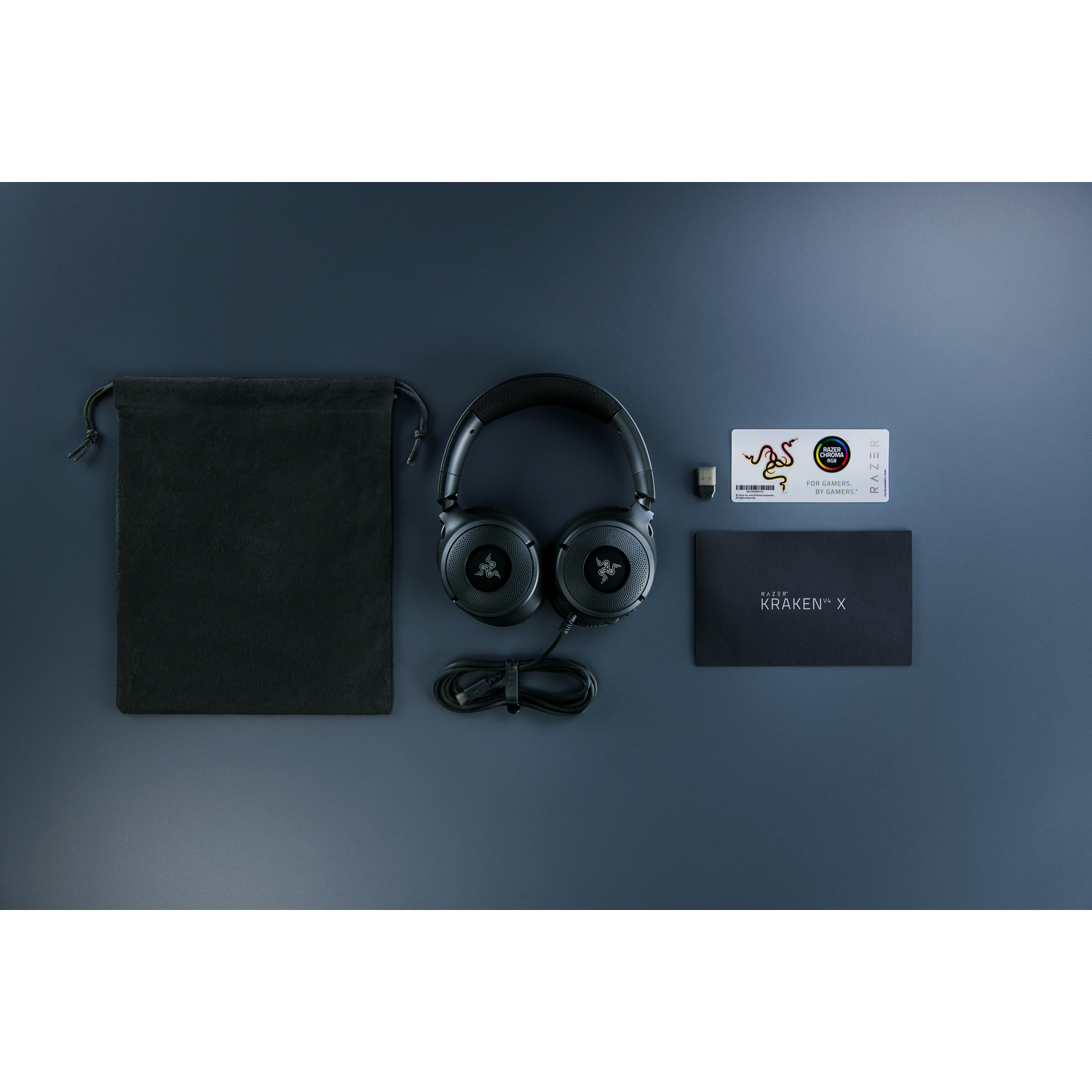 Black headphones, charging cable, carrying bag, and a card, arranged on a dark blue surface.