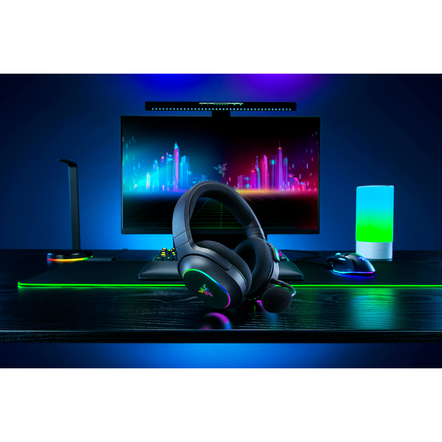 Gaming setup with headphones on a desk, monitor, mouse, and a desk lamp.