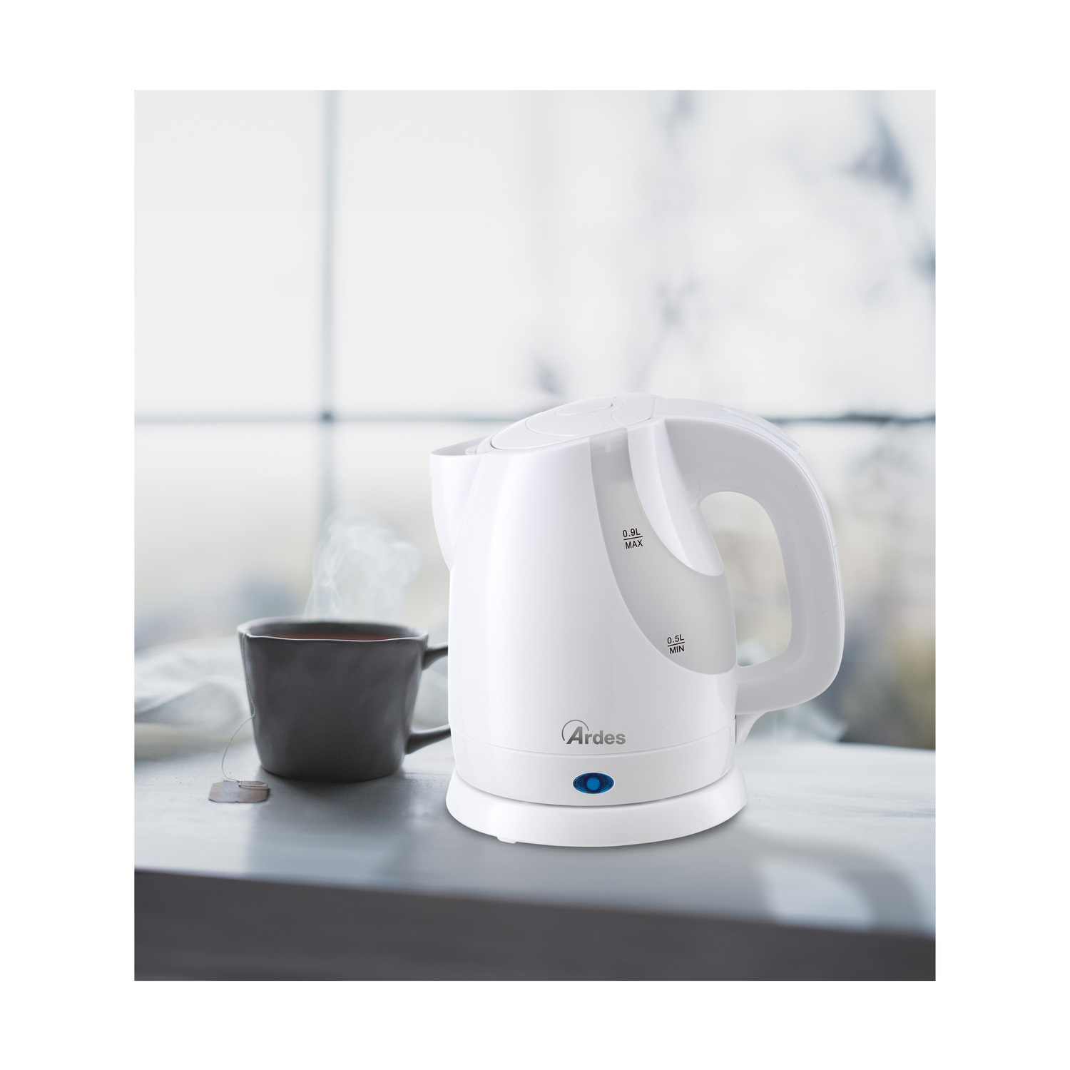 Bollitore elettrico bianco con tazza di tè nera. Una bustina di tè è sul tavolo.
