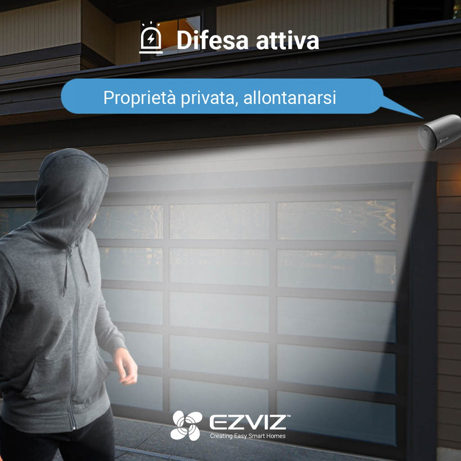 Una persona con la felpa con cappuccio si avvicina a una porta del garage di notte, con una telecamera di sicurezza visibile.