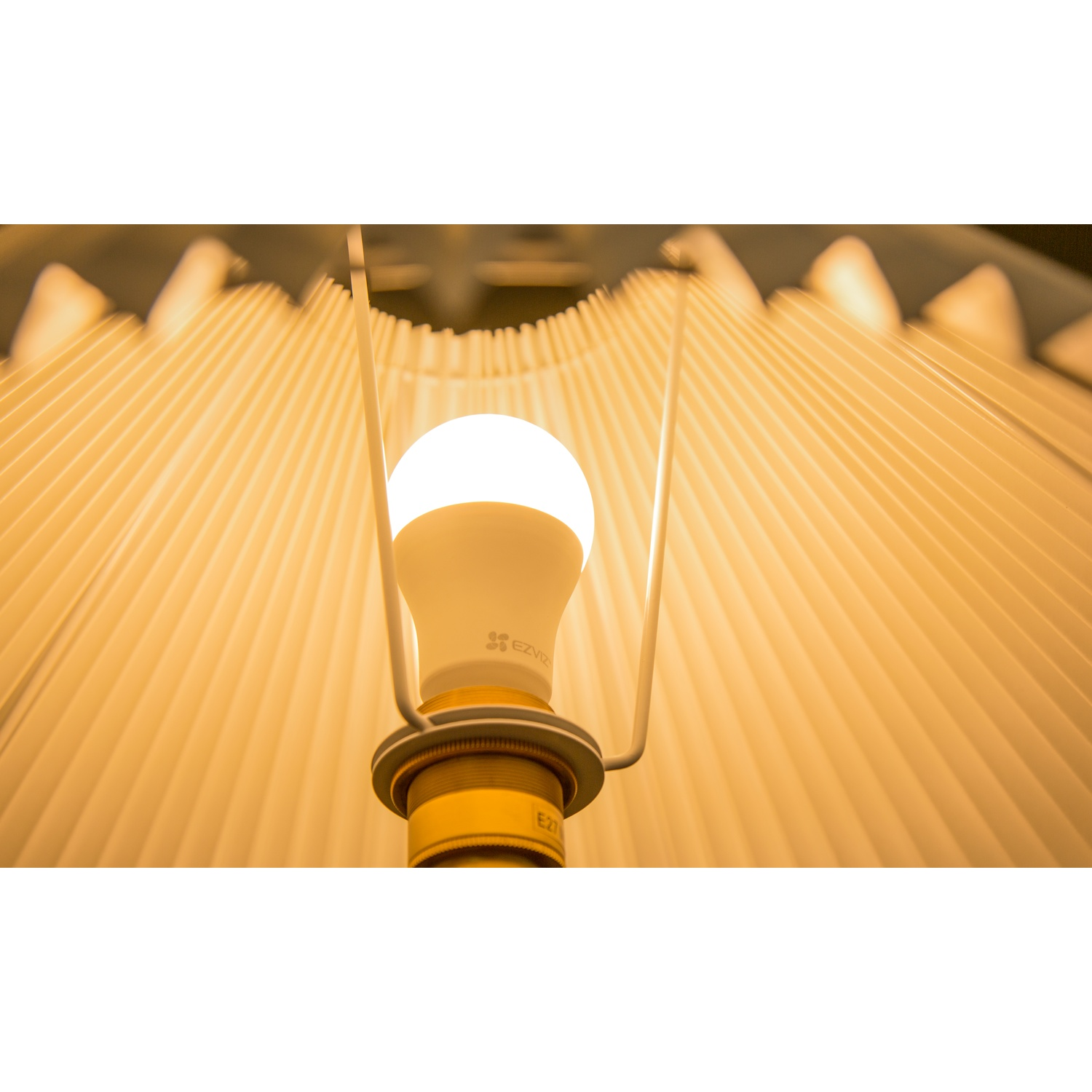 Lampadina accesa in una lampada. Sfondo bianco con una tonalità gialla.