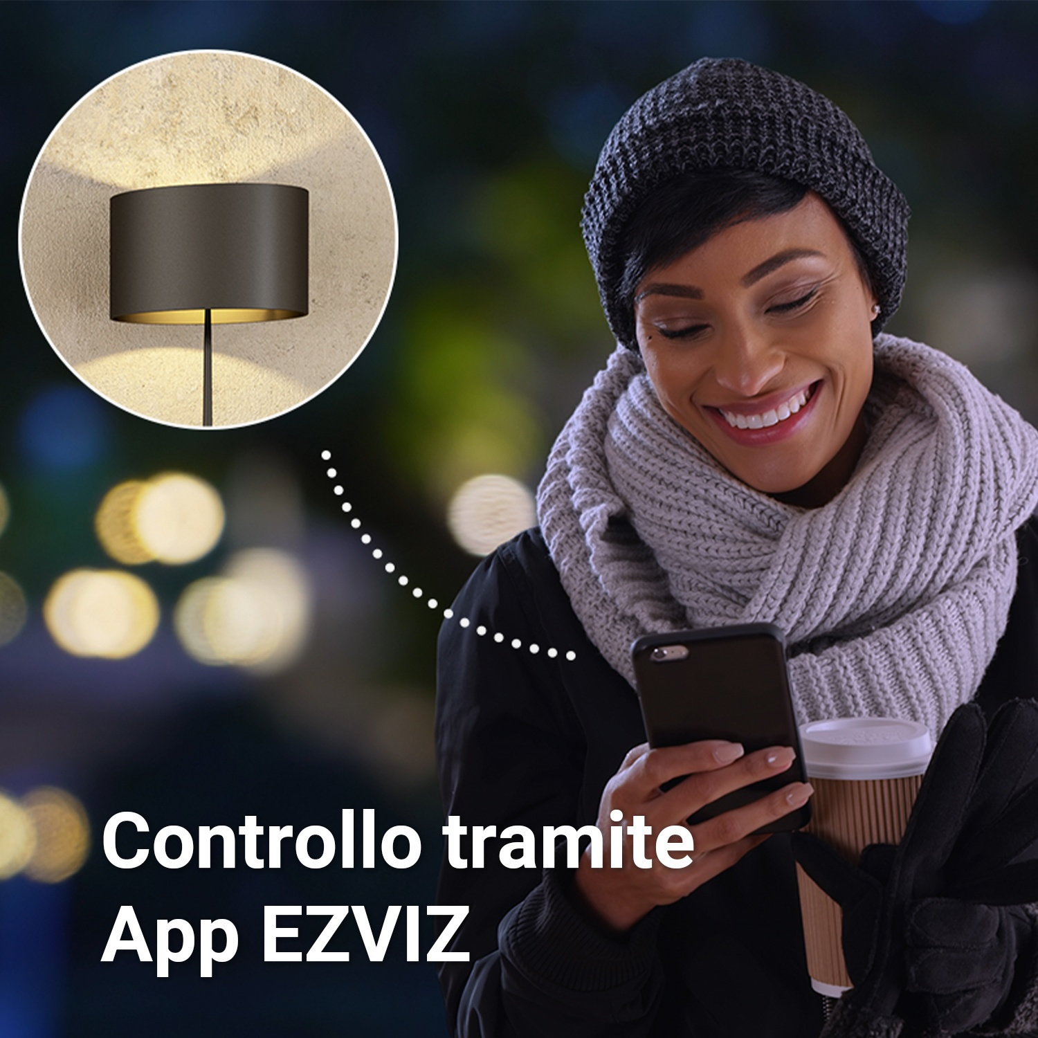 Una donna sorride mentre tiene un telefono e un caffè, con un lampione sullo sfondo.
