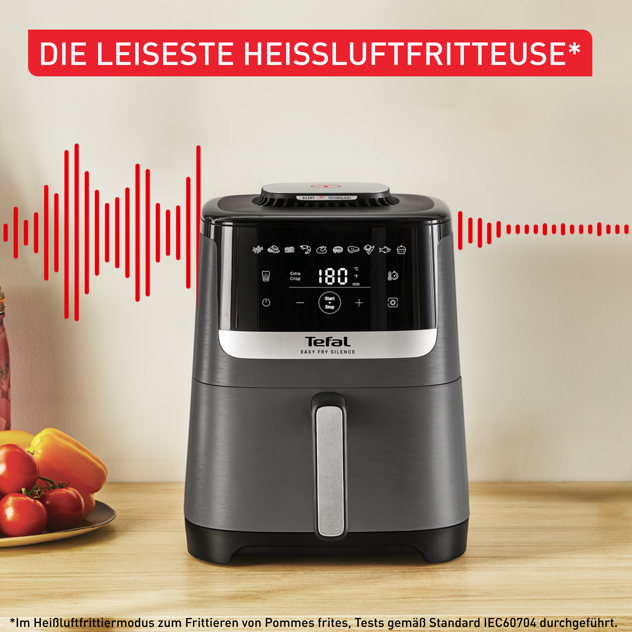 Schwarze Heißluftfritteuse auf Holzoberfläche. Rote Schallwellen links. Text: 'Die leiseste Heißluftfritteuse'.