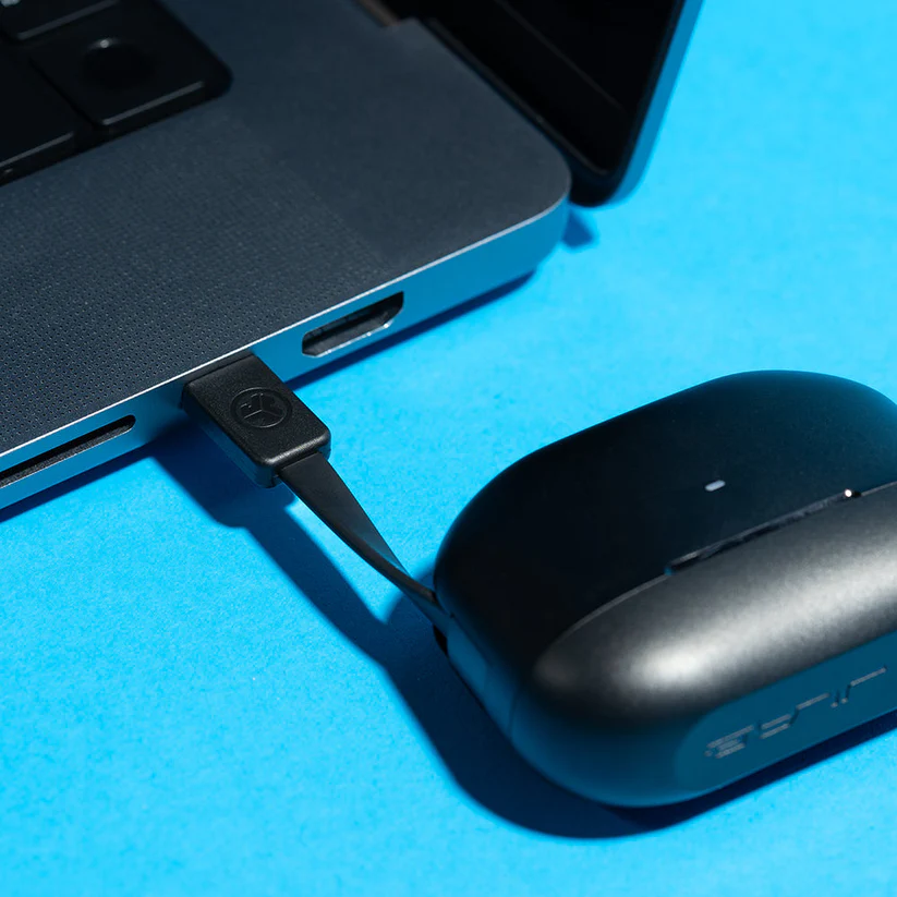 Ein schwarzes Ladekabel ist an einen Laptop angeschlossen. Ein schwarzes Ladegerät befindet sich auf einer blauen Oberfläche.