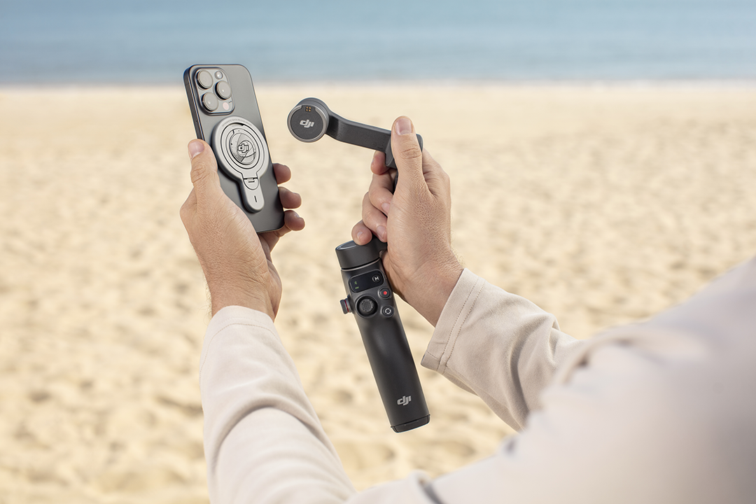 Egy személy egy okostelefont tart egy gimbal-lal a strandon.