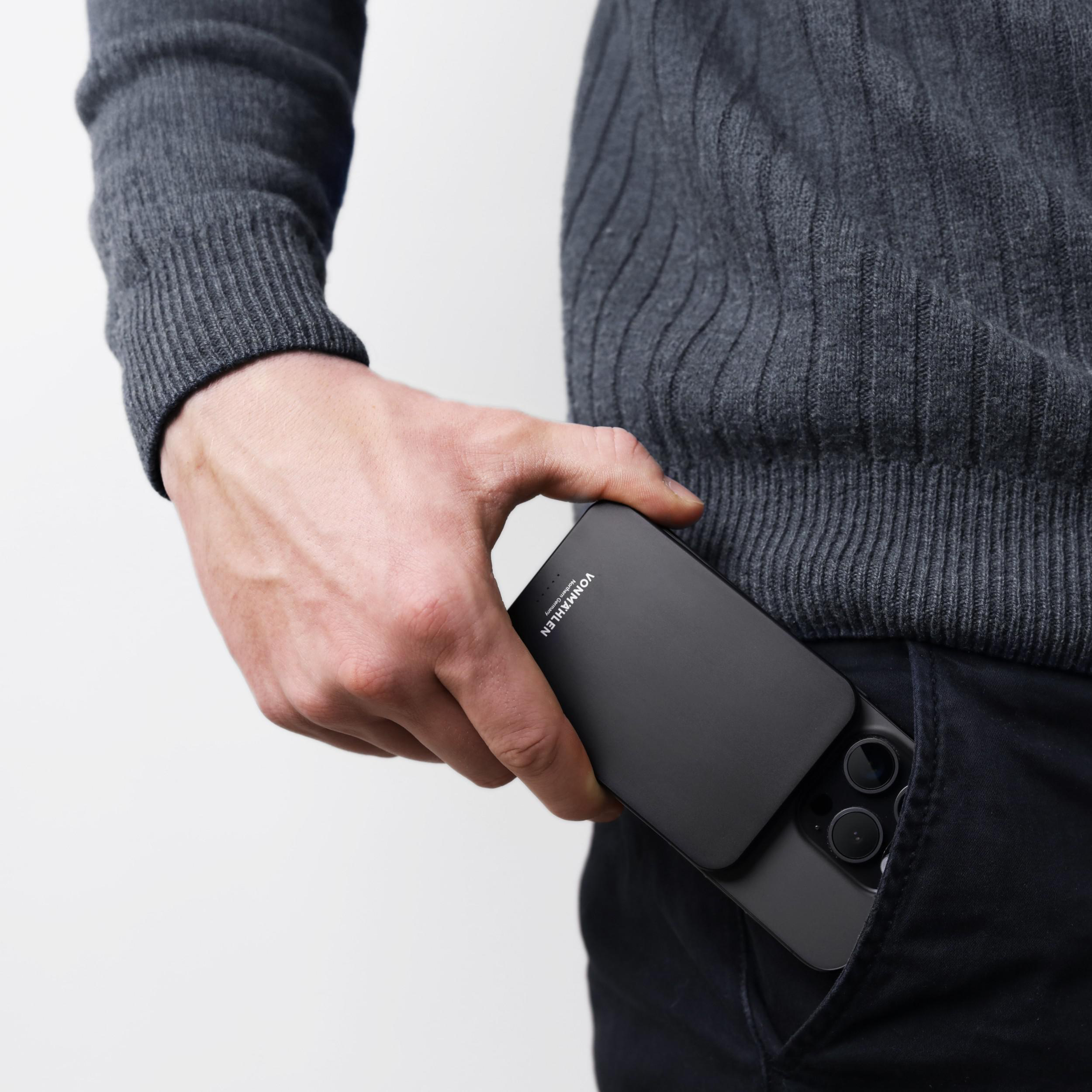Eine Person, die ein Telefon und eine schwarze Handyhülle in der Tasche hält.