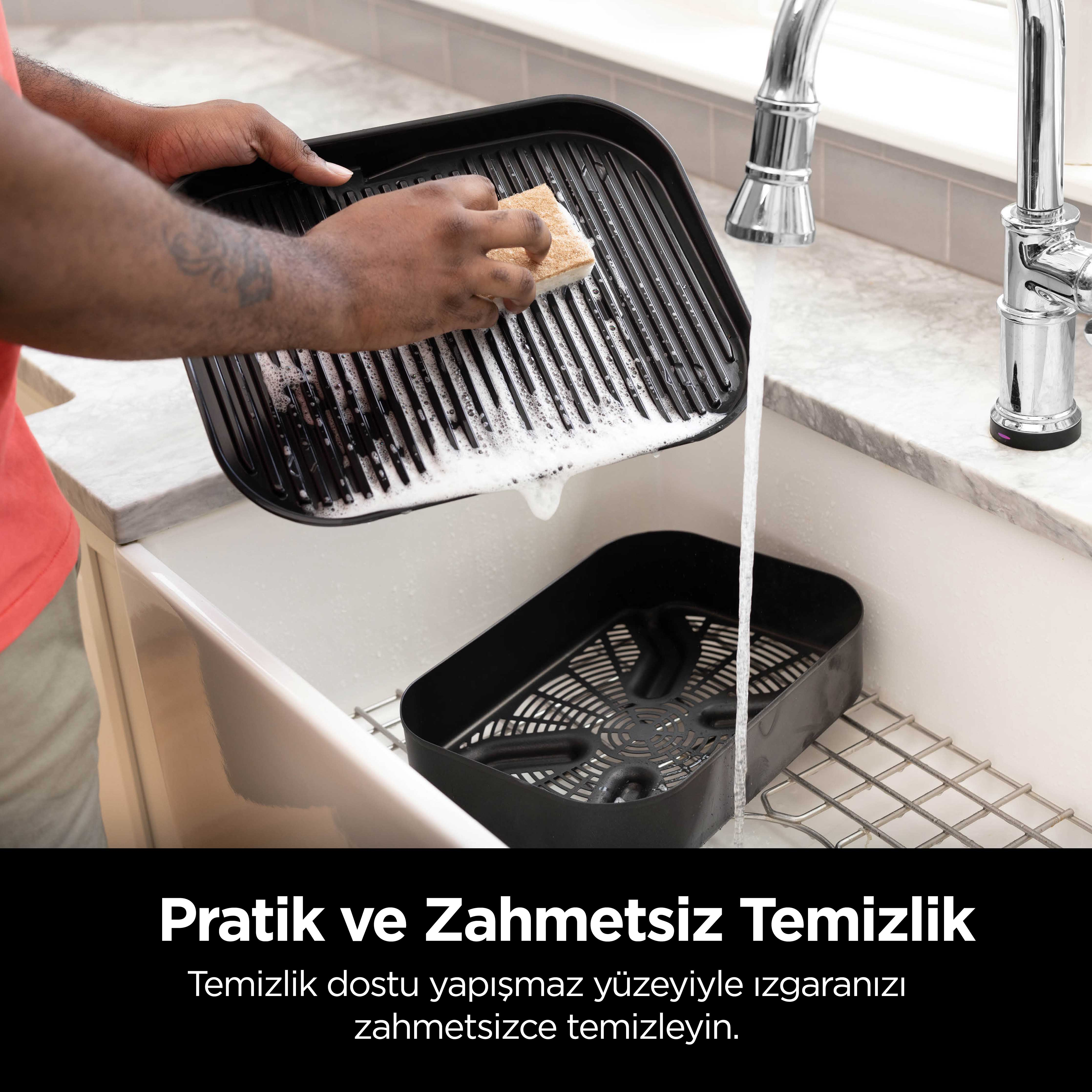 Siyah bir ızgarayı süngerle temizleyen kişi, arka planda lavabo ve musluk.