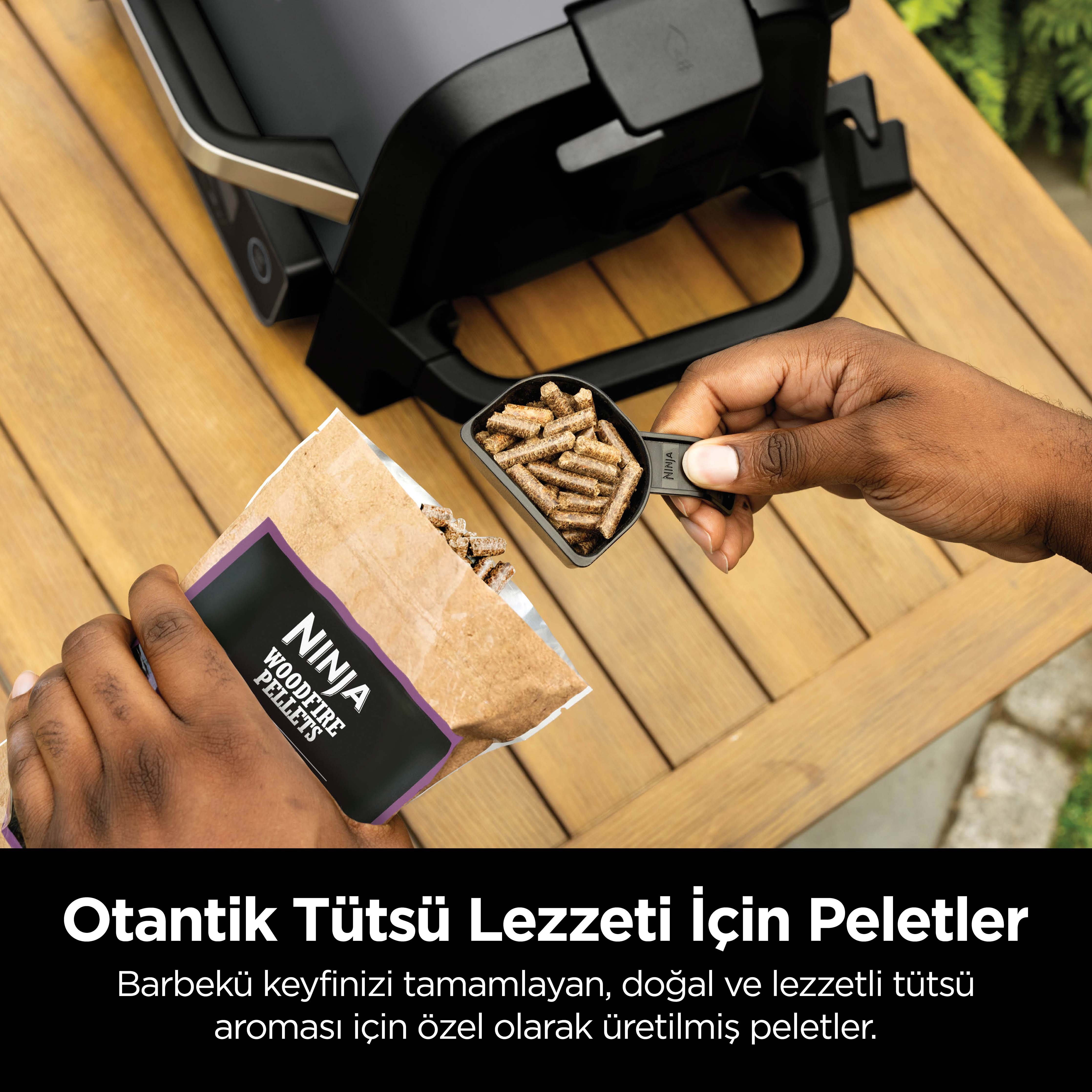 Bir el tahta peletleri kepçesi tutuyor, Ninja pelet torbası ve arka planda ızgara.