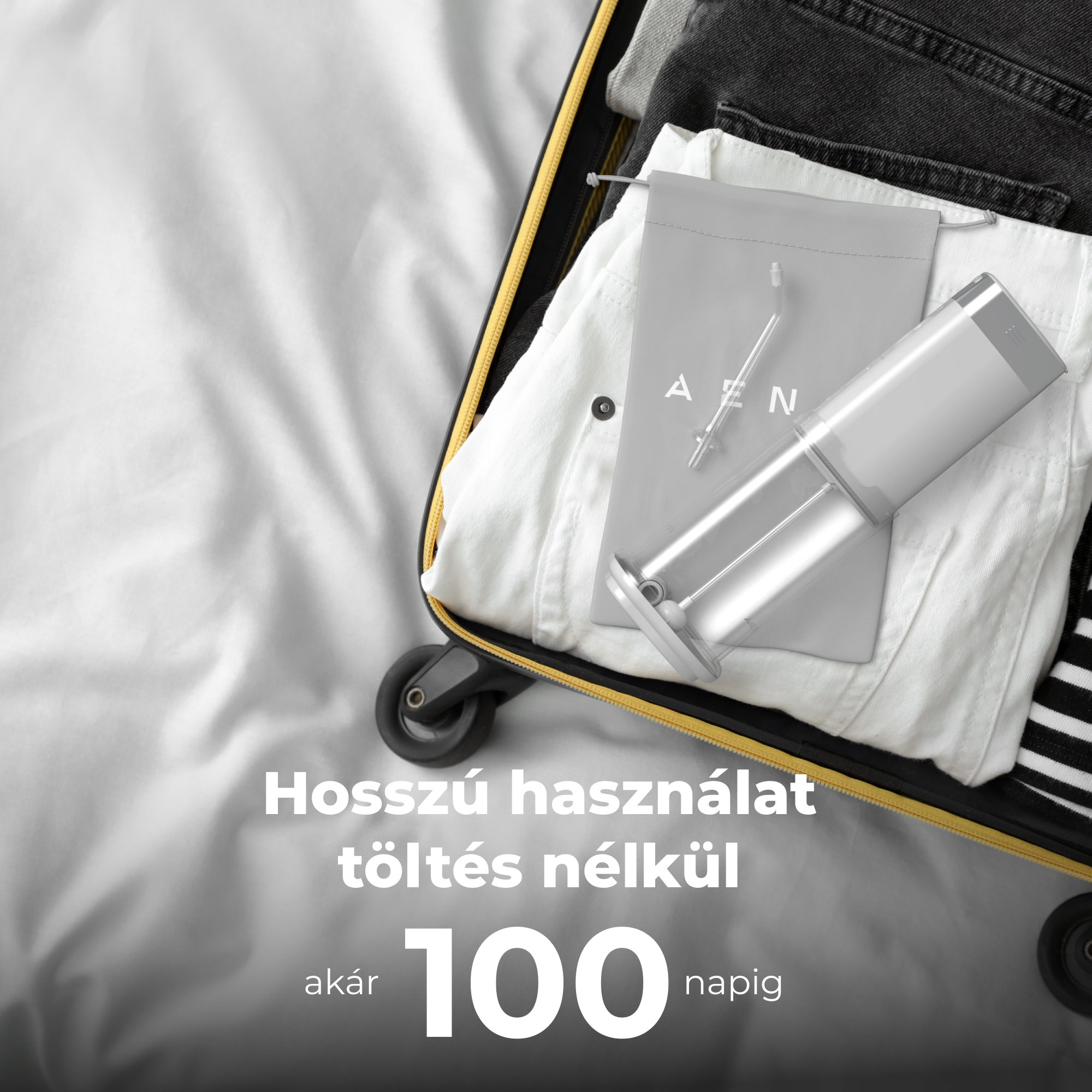 Nyitott bőrönd egy ezüst készülékkel és ruhákkal benne. Fehér háttér.