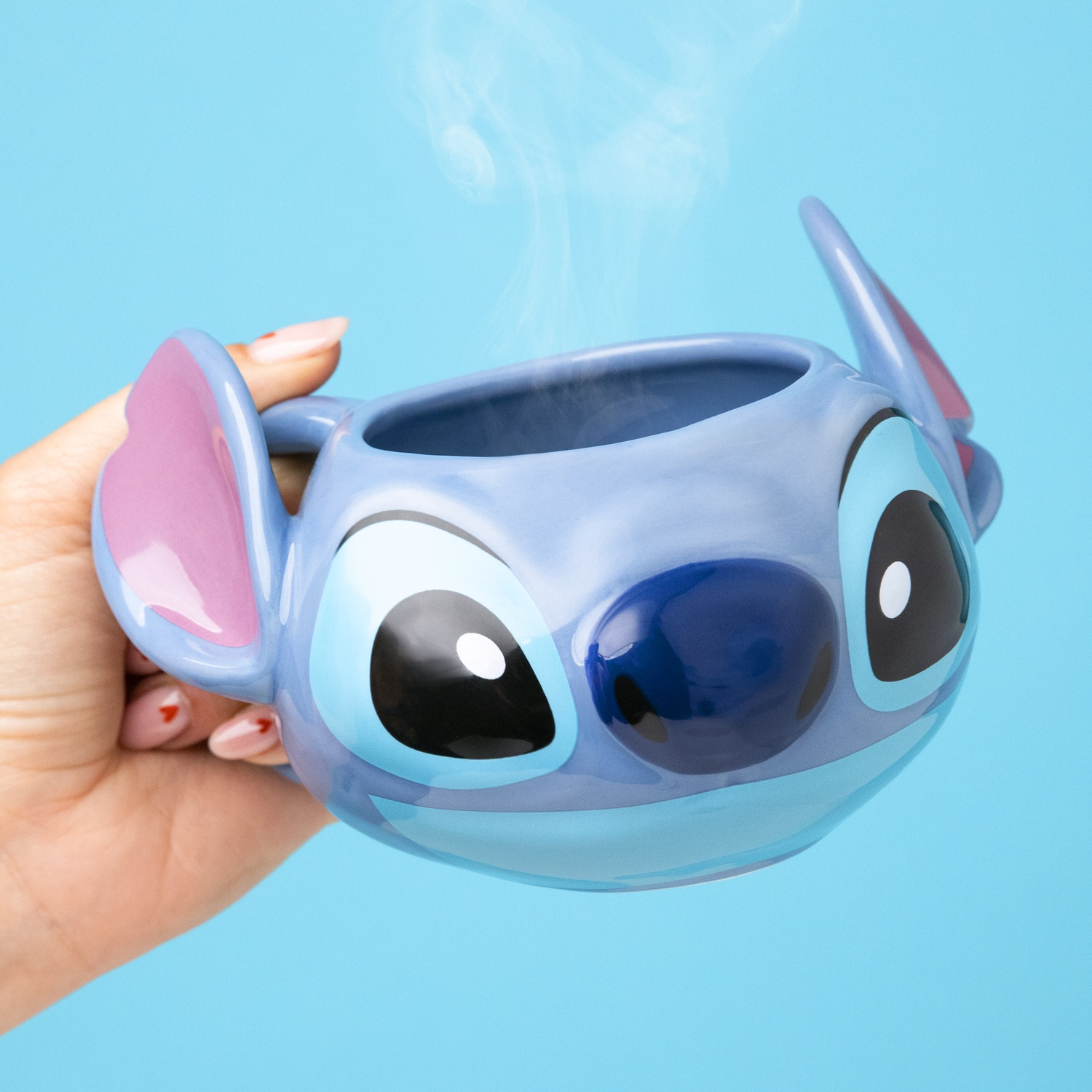 Stitch mug in hand, steam rising, blue background.