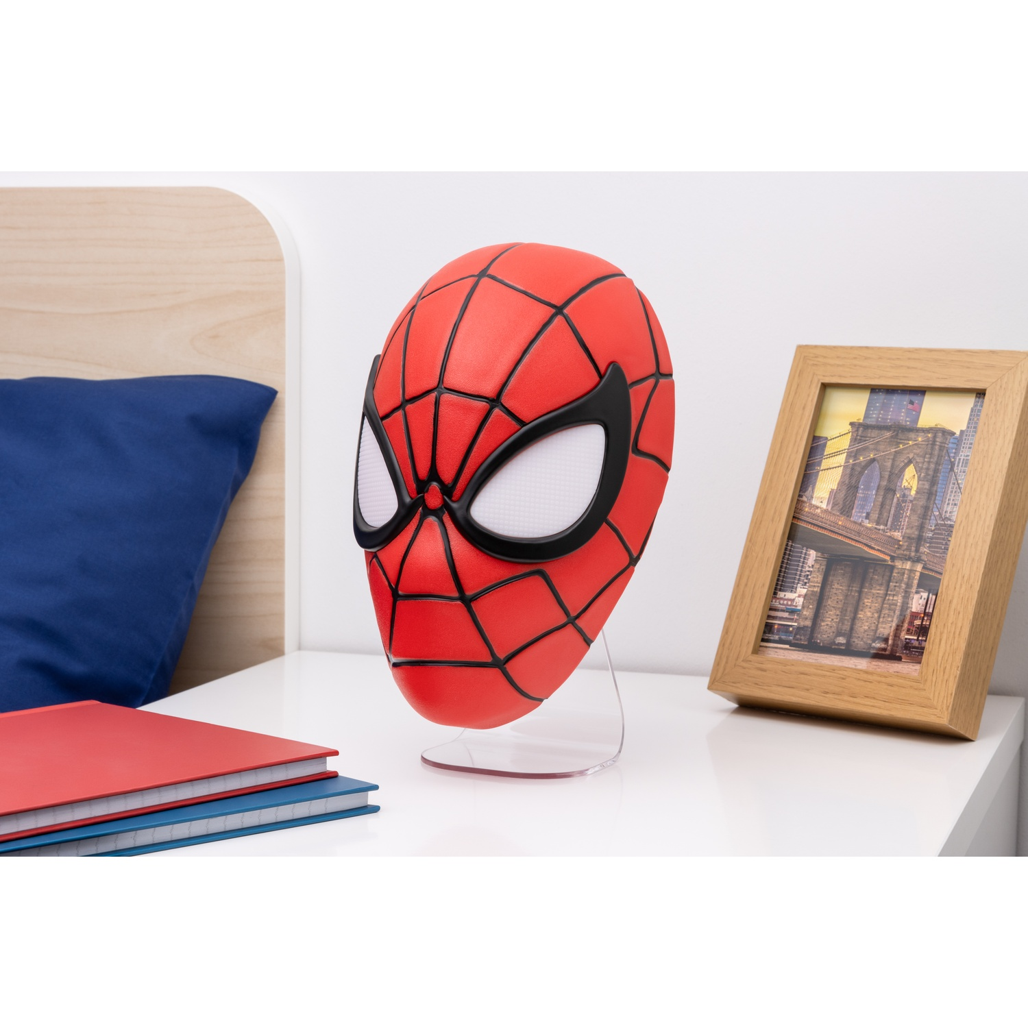 Een Spiderman-masker op een standaard, naast boeken en een fotolijst.