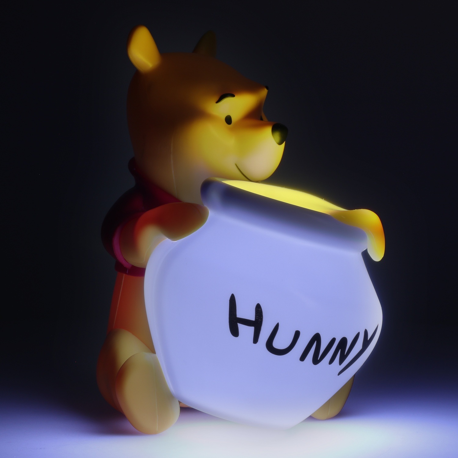 Figurine Winnie l'ourson tenant un pot lumineux avec 'HUNNY'.