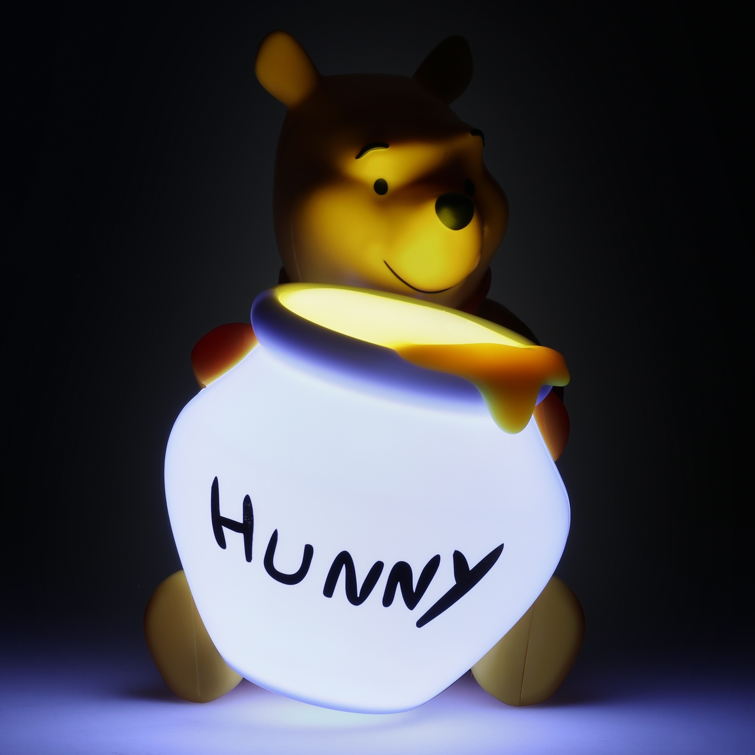 Lampe Winnie l'Ourson tenant un pot de miel brillant. Le mot 'HUNNY' est écrit dessus.