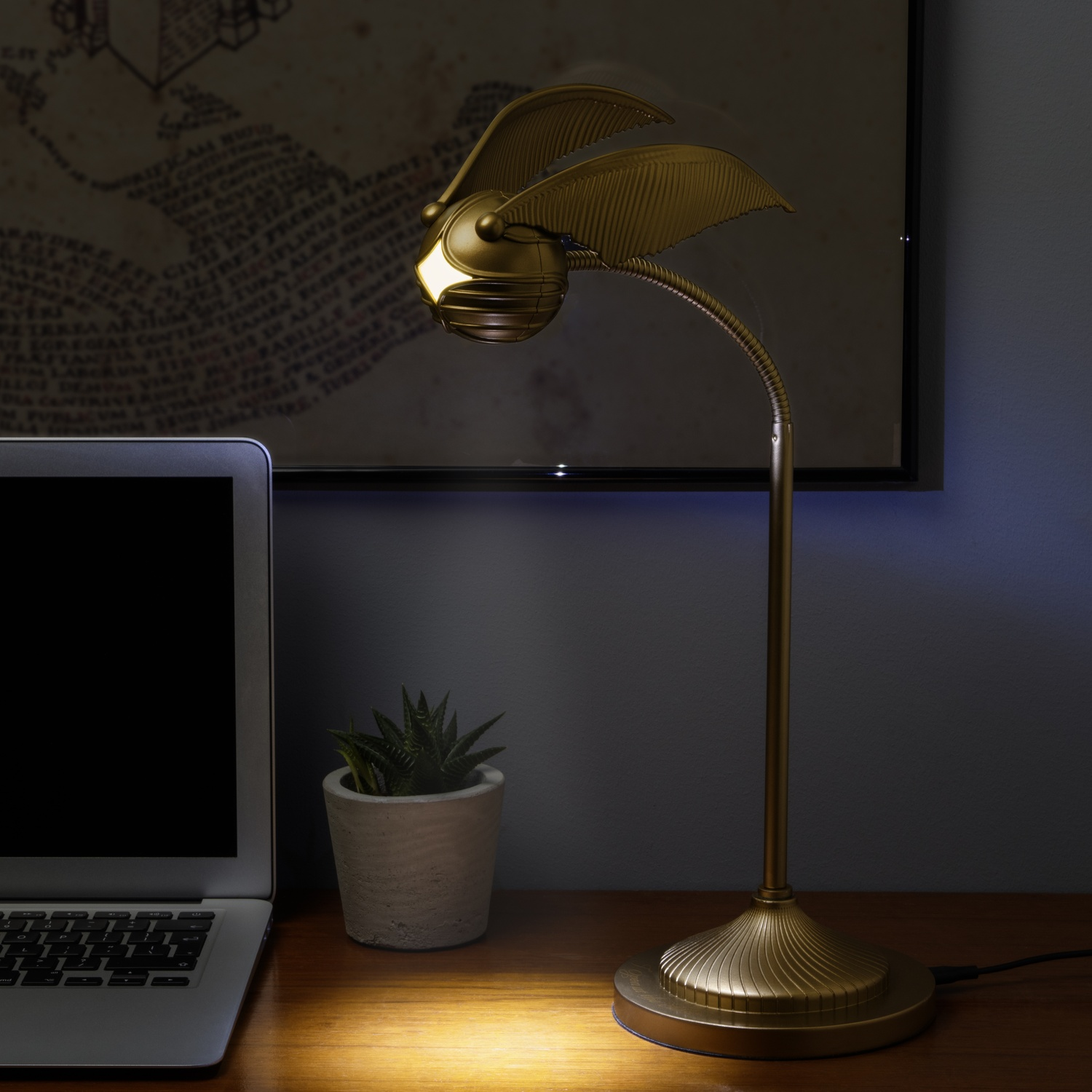 Een gouden lamp in de vorm van een snaai staat op een houten bureau met een laptop.