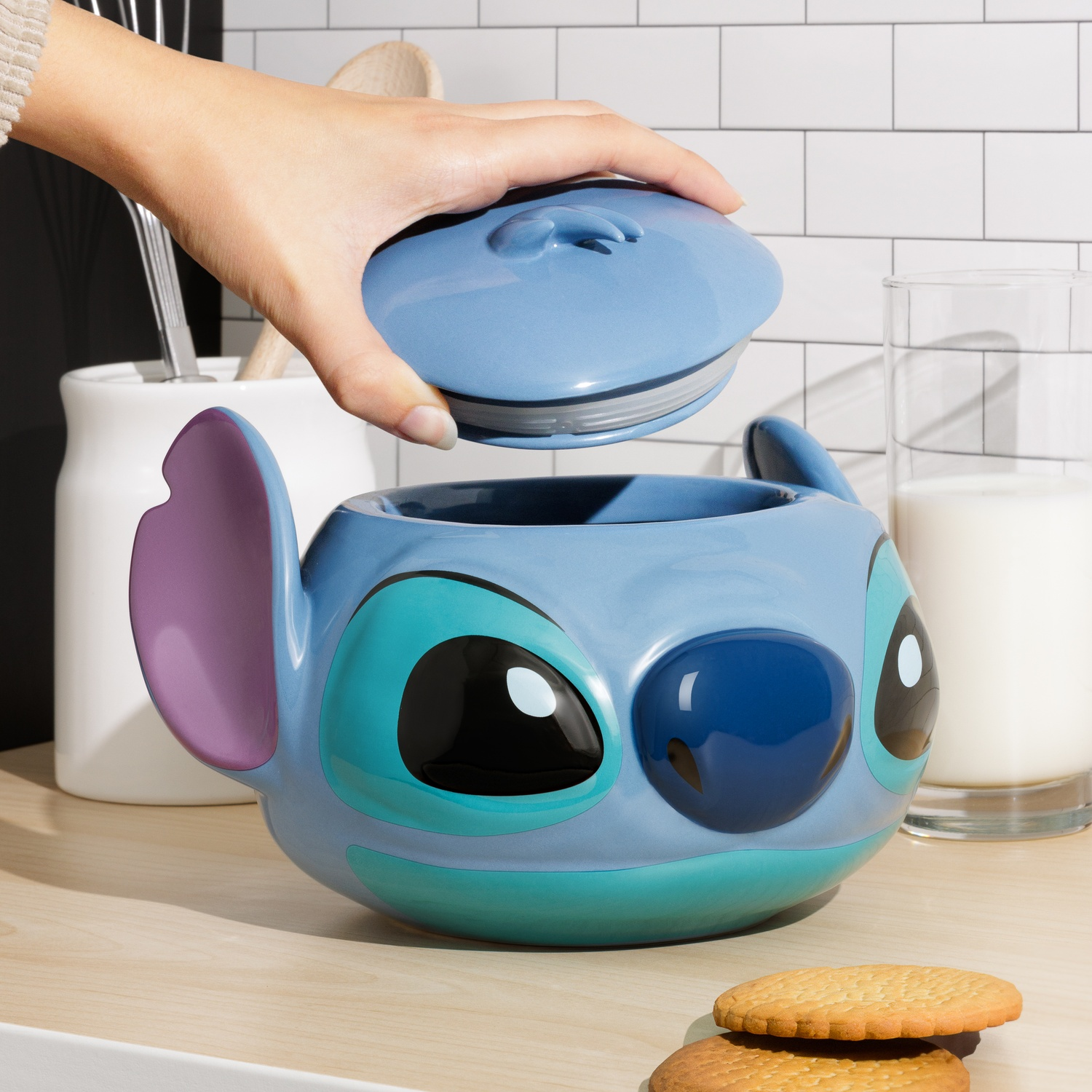 Blue Stitch mug with lid, a hand removing it, and cookies and milk near.