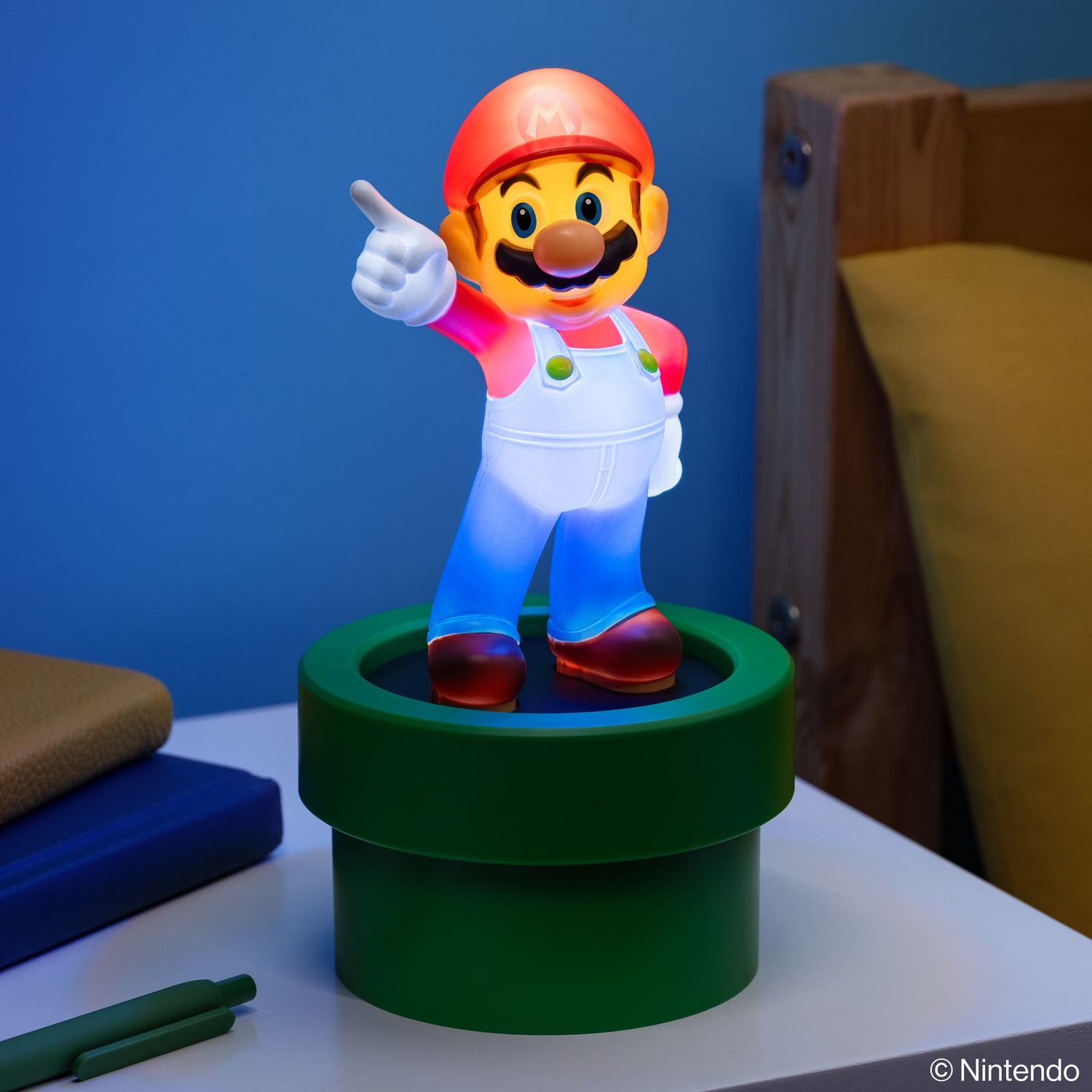 Mario light figure standing on a green pipe. He is giving a thumbs up. Blue wall in the background.